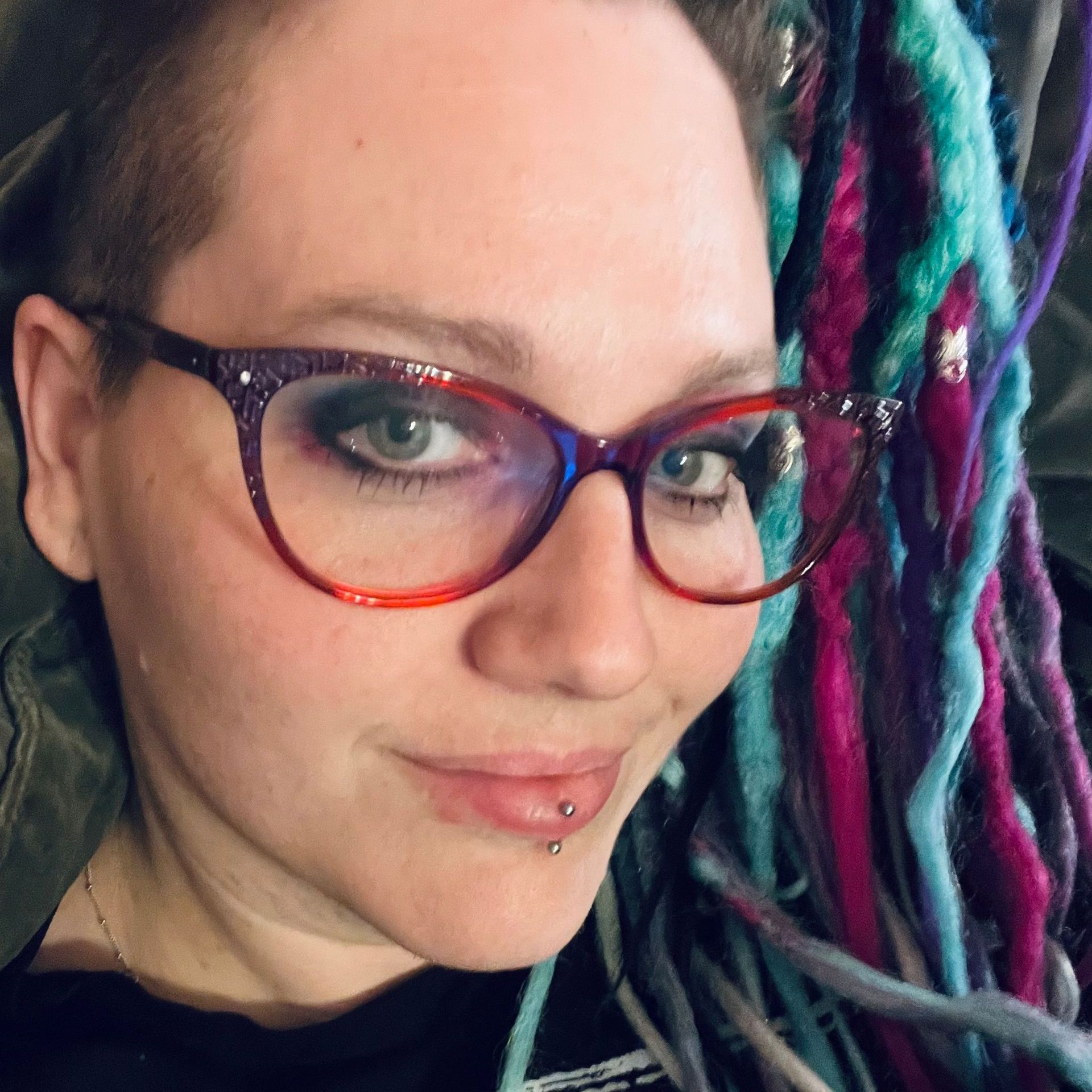 A close up of a woman wearing glasses and dreadlocks
