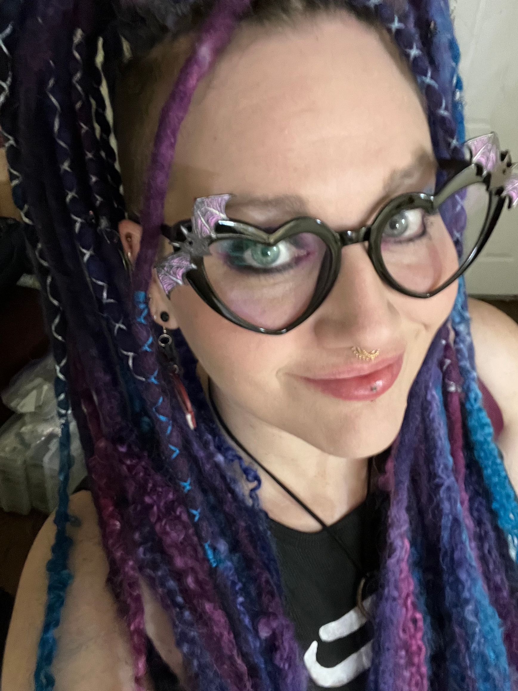 A woman with purple and blue dreadlocks wearing glasses