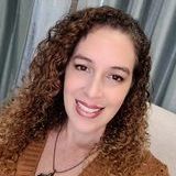 A woman with curly hair is smiling and wearing a necklace.
