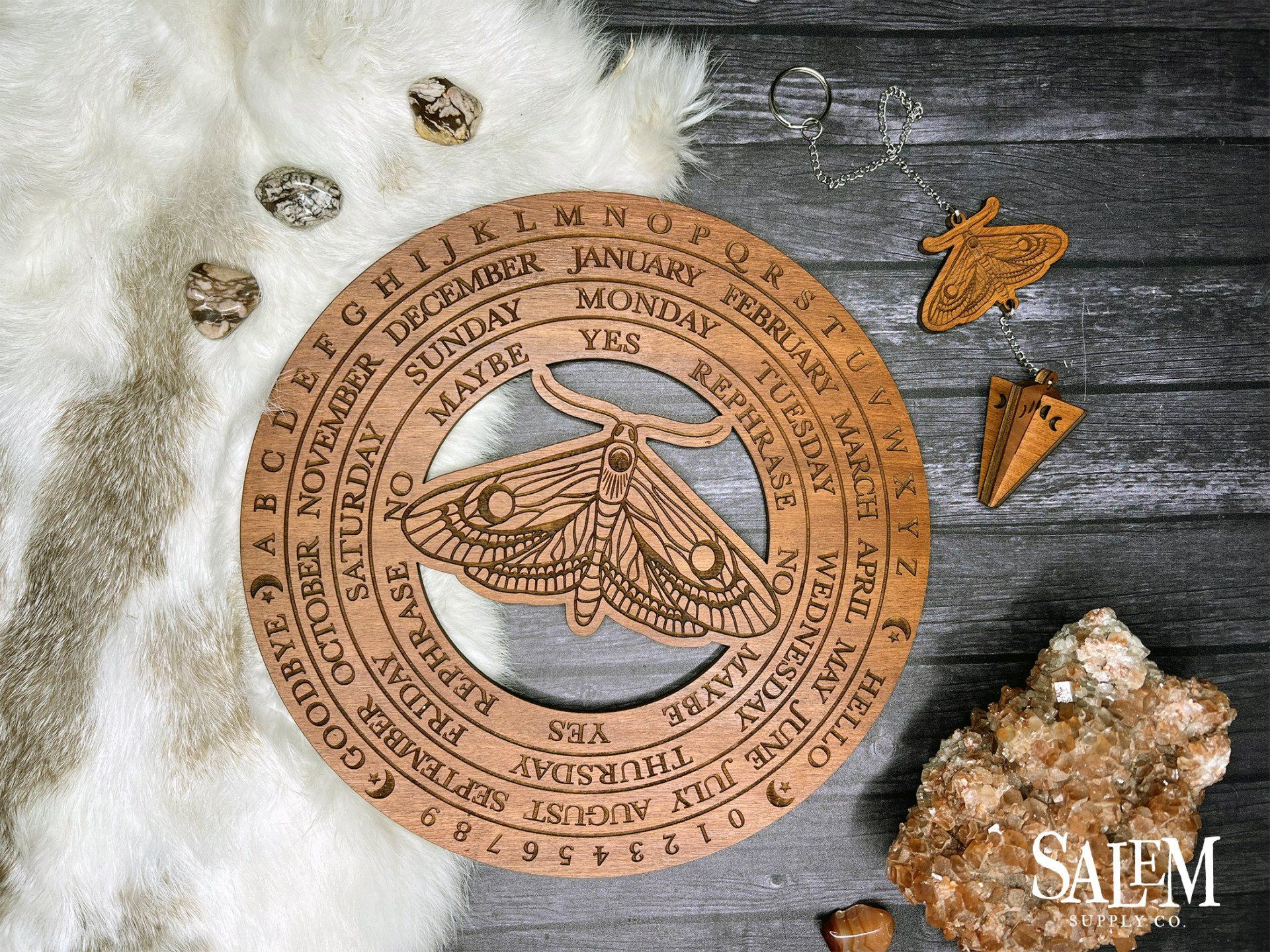 A wooden circle with a moth on it is sitting on a wooden table.