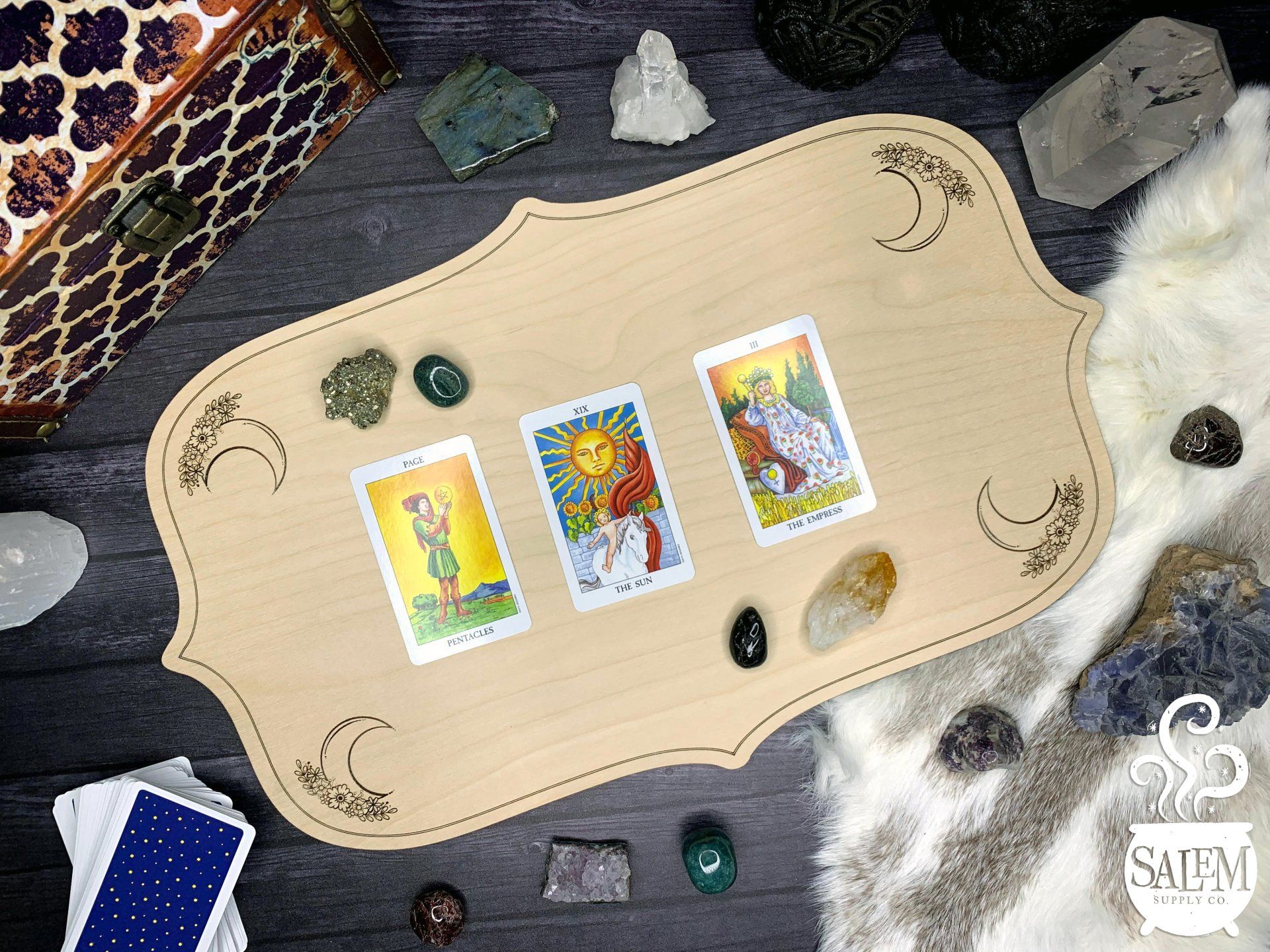 A wooden table with tarot cards and crystals on it.
