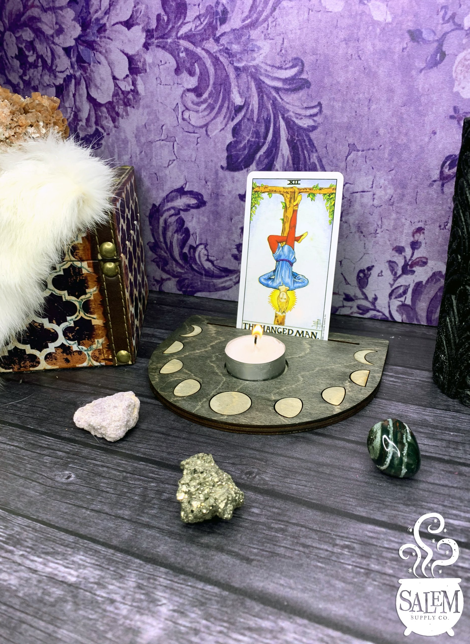 A tarot card is sitting on a wooden table next to a candle.