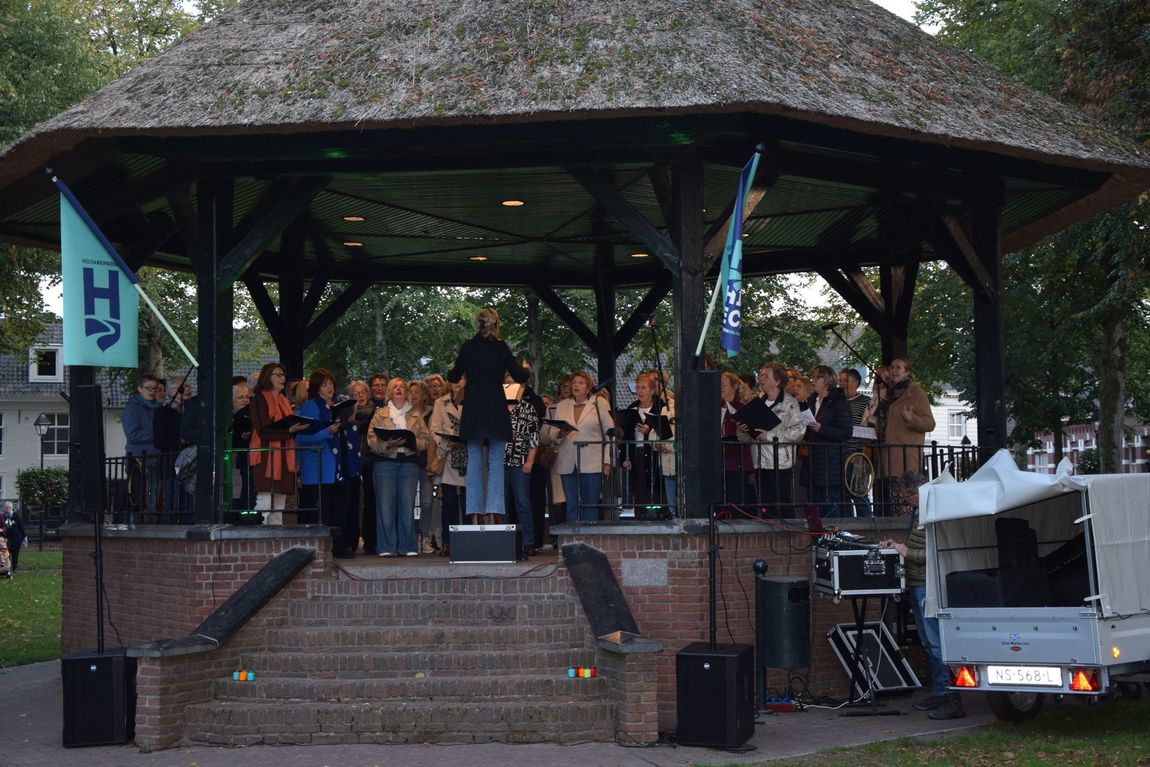 De opening van De Nacht van het Gemis op de kiosk met een koor de bontekakelkippen, te zien vanuit het publiek.