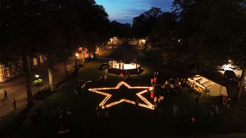 De Vrijthof 's avonds met een grote, verlichte sterrencontour en mensen eromheen verzameld.