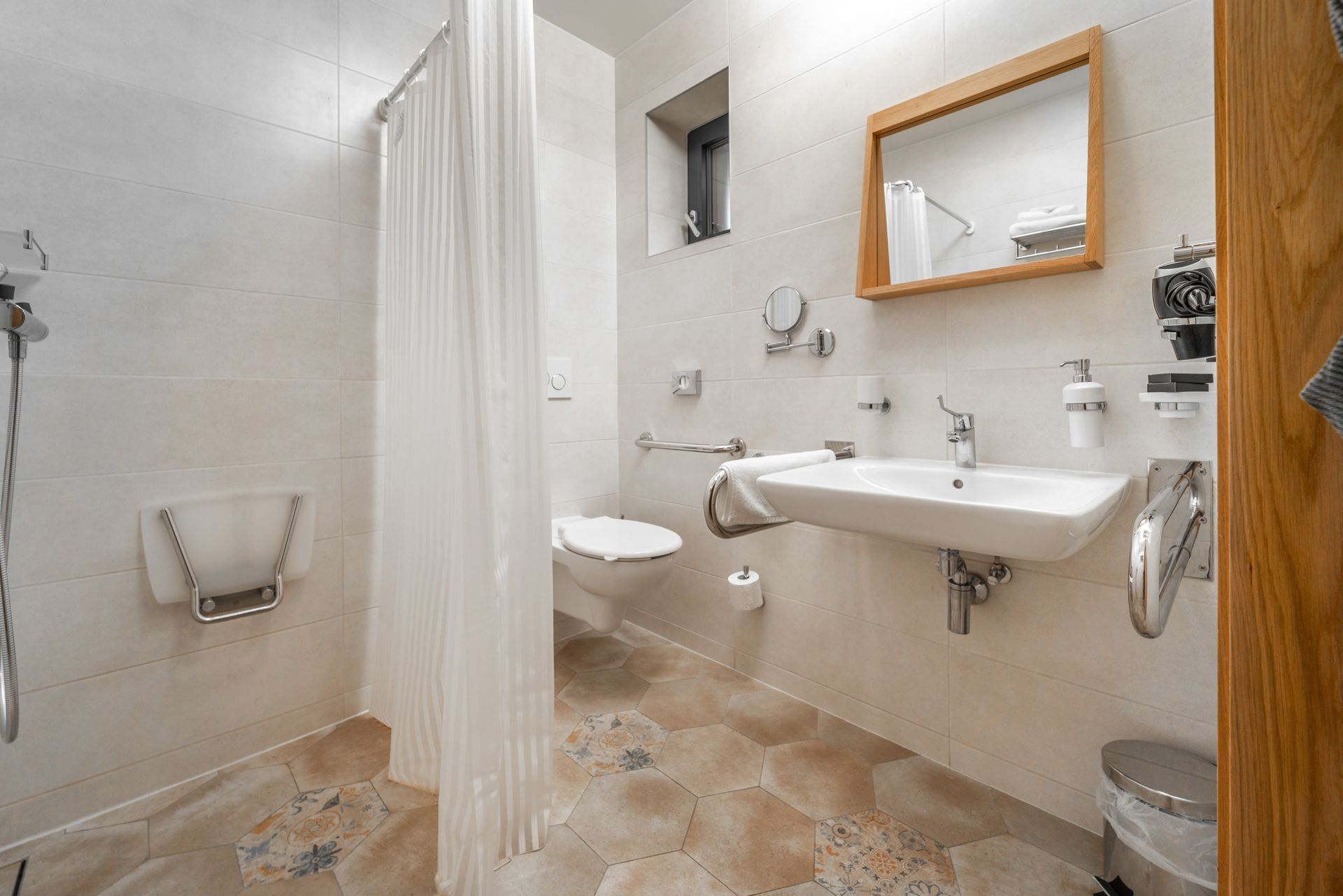 A modern bathroom with a white vanity, a large rectangular mirror, and beige tiled walls and floors.