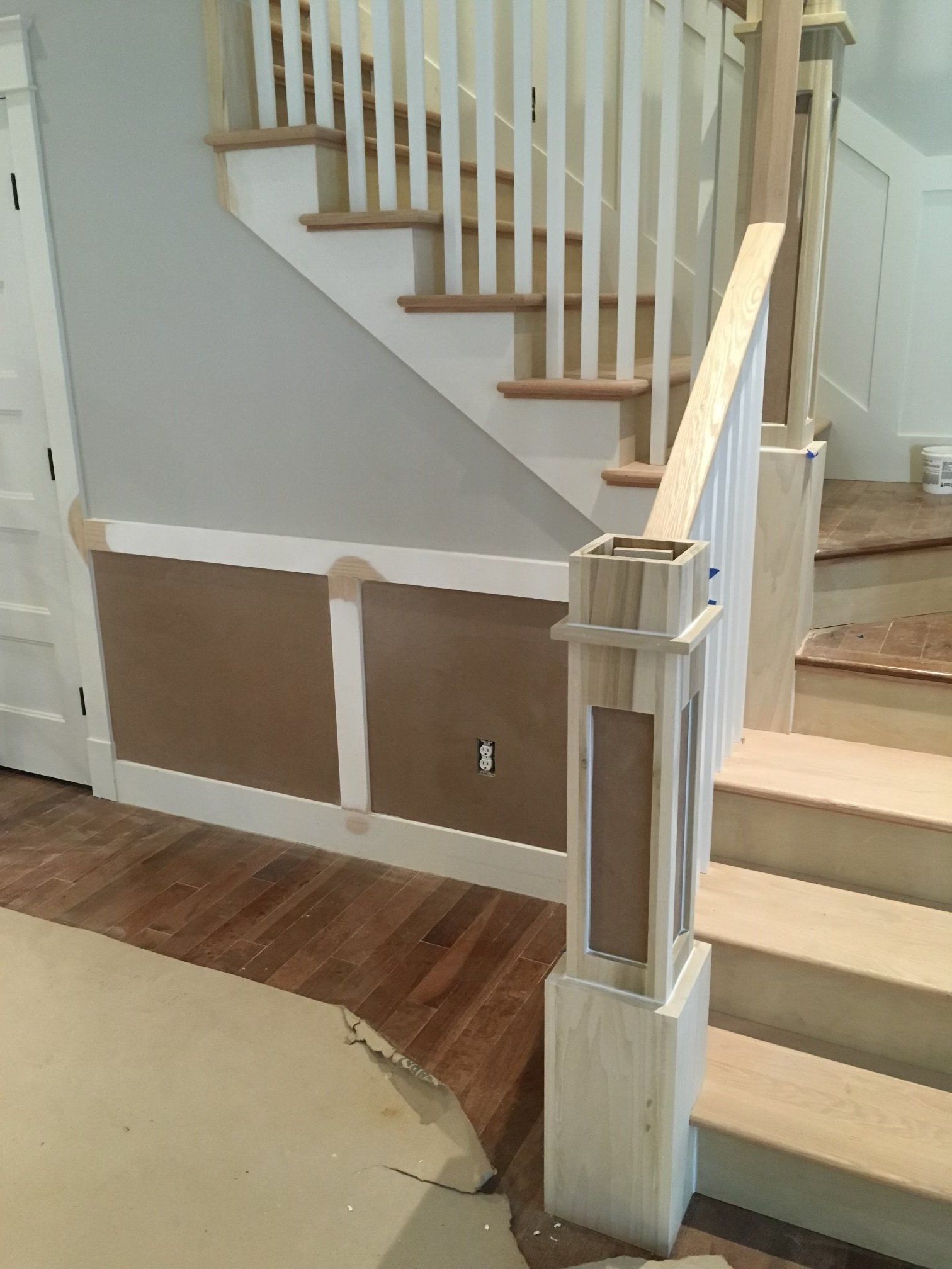 Interior staircase with white railings, brown wall paneling, and beige carpeted steps