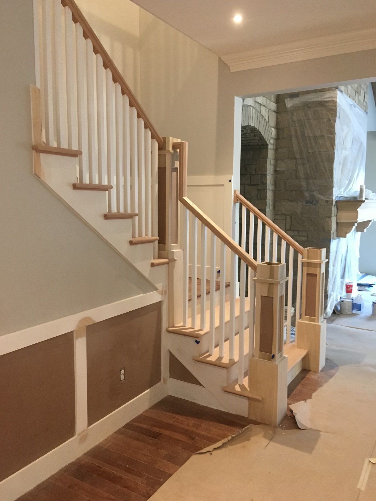 Interior staircase with white balusters, wooden handrails, and hardwood floor in a hallway
