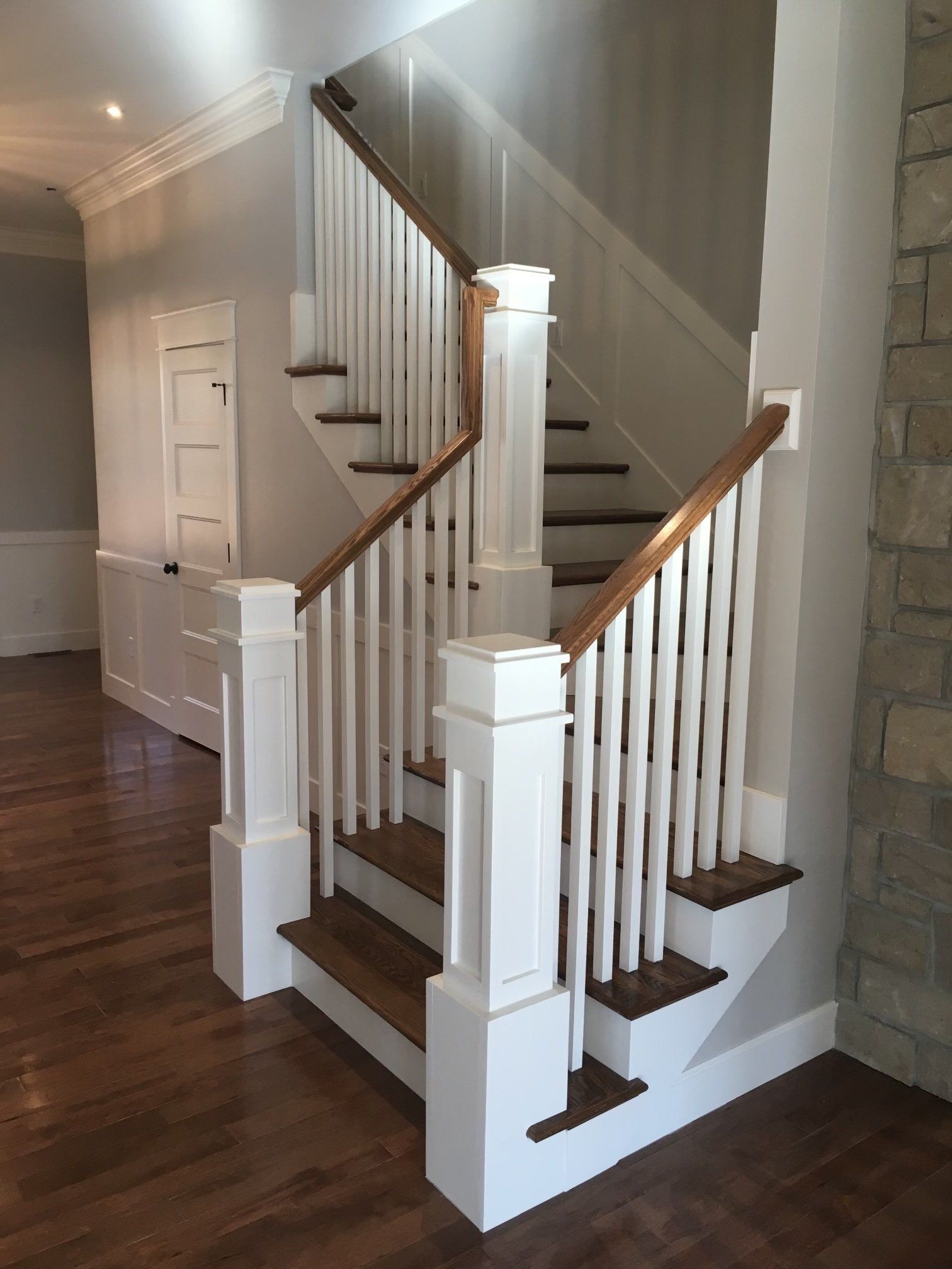Indoor staircase with white balusters, dark wood steps, and a wood handrail in a home hallway