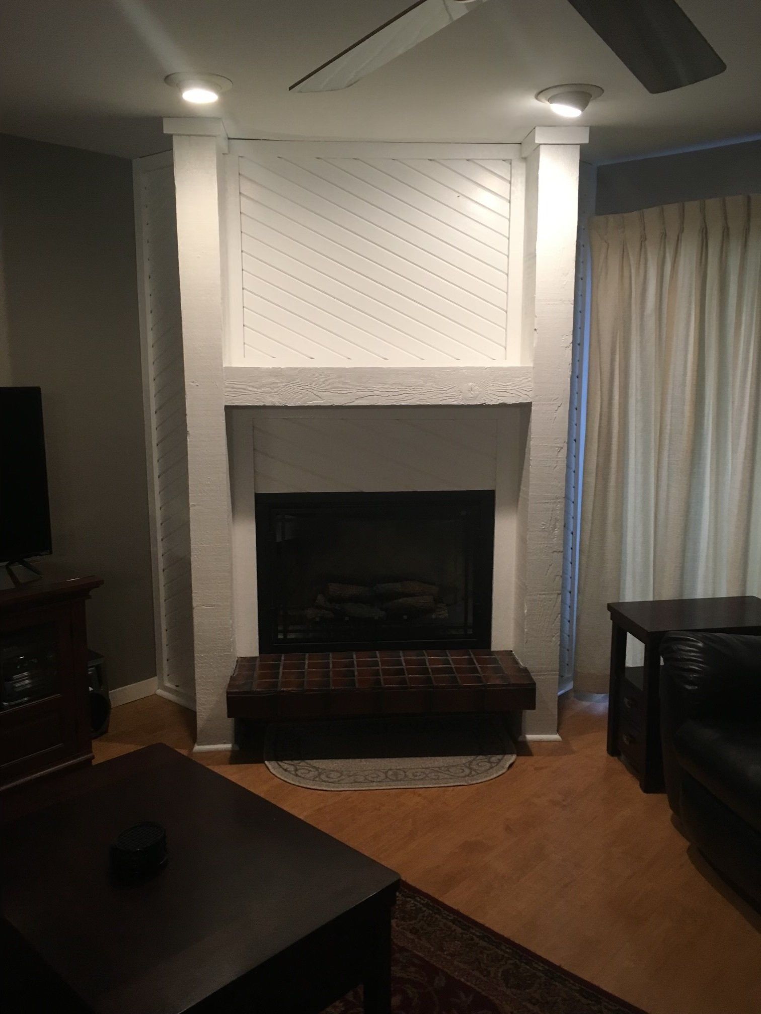 Living room with a white fireplace mantel, dark hearth, curtains, and ceiling fan