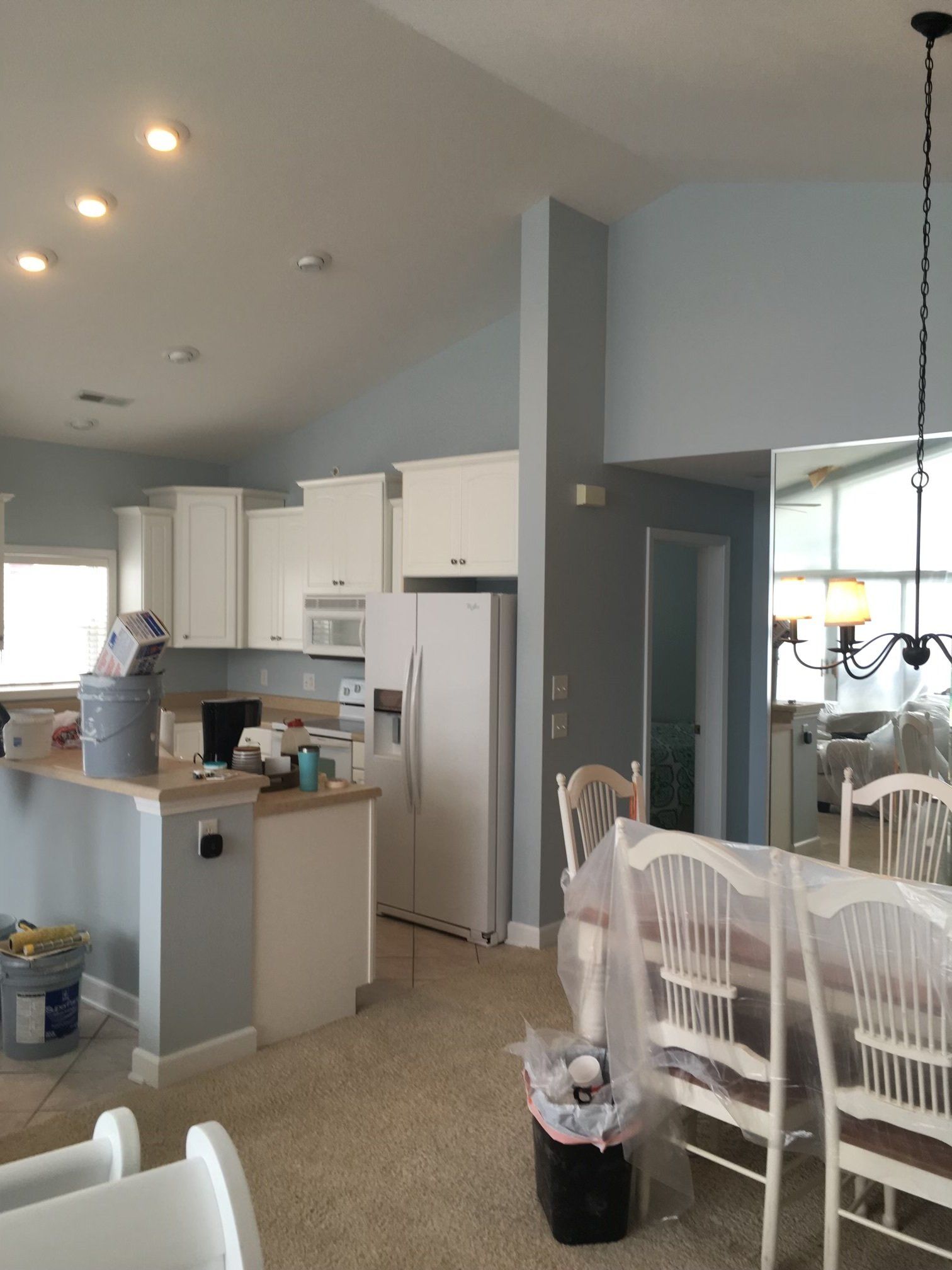 Bright kitchen and dining area with white cabinets, island, chairs, and a large window.
