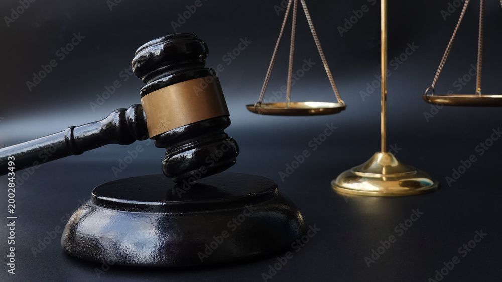 Judge's gavel beside balanced scales on a dark law-themed background