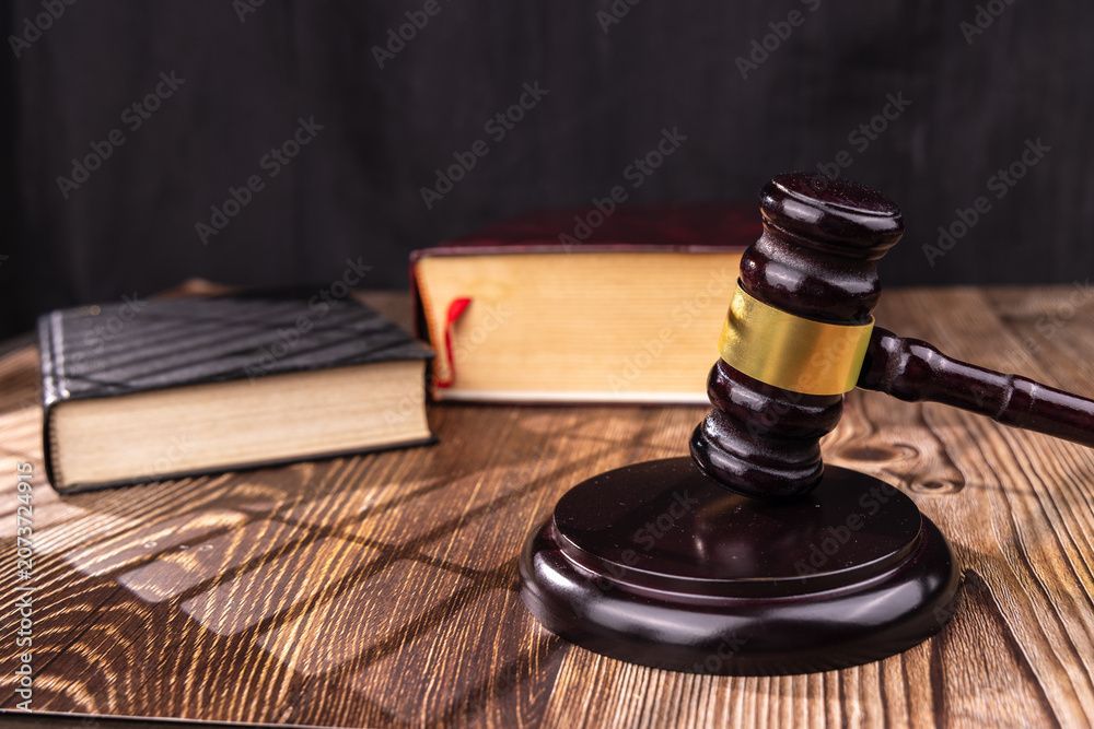 Judge’s gavel resting on a wooden desk beside law books, symbolizing legal services.