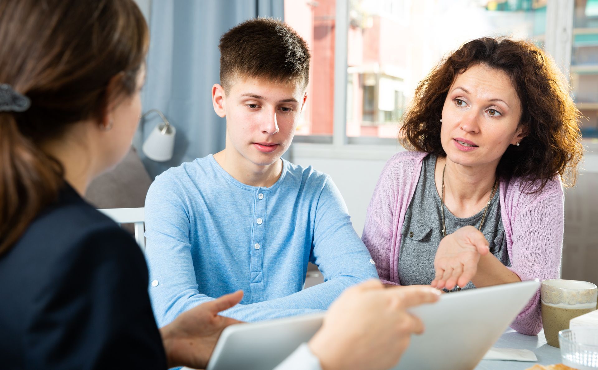 Mother and teenage son talking with a criminal justice lawyer about juvenile charges