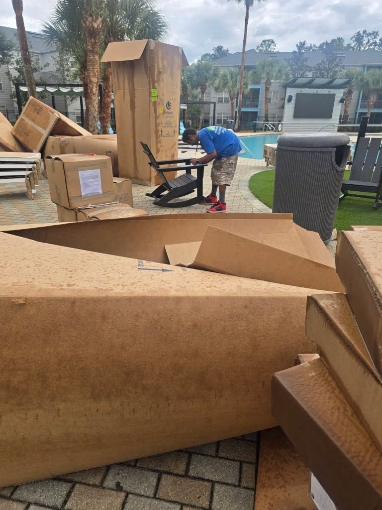 Person unloading large cardboard boxes beside a pool outdoors