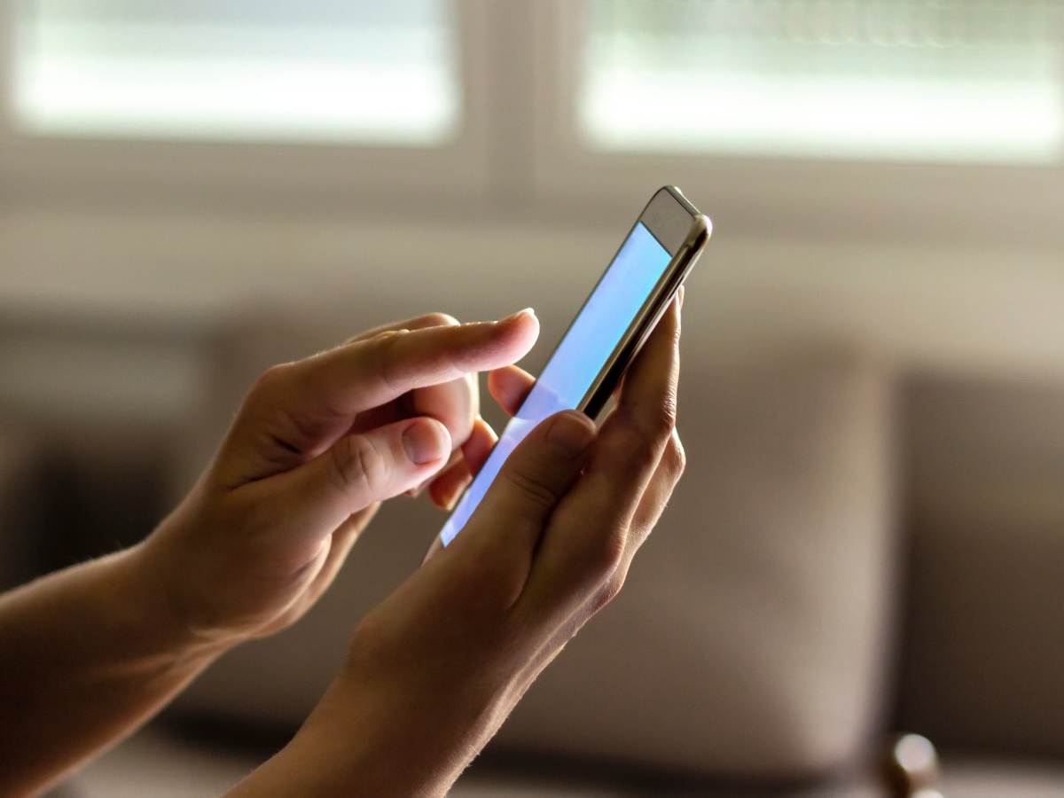 a person is using a cell phone with a blue screen .