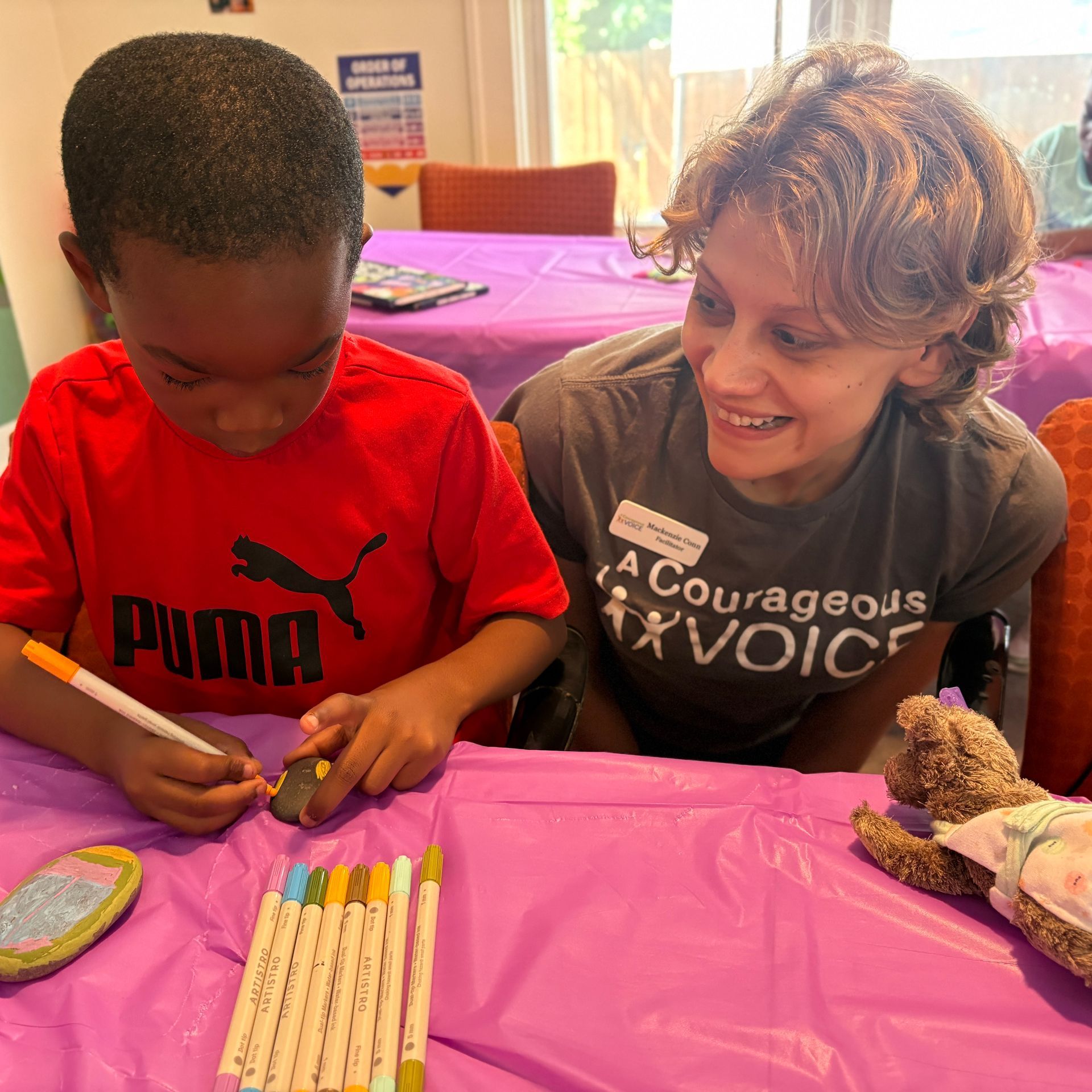 Child and adult coloring together at a table with crayons on a purple tablecloth
