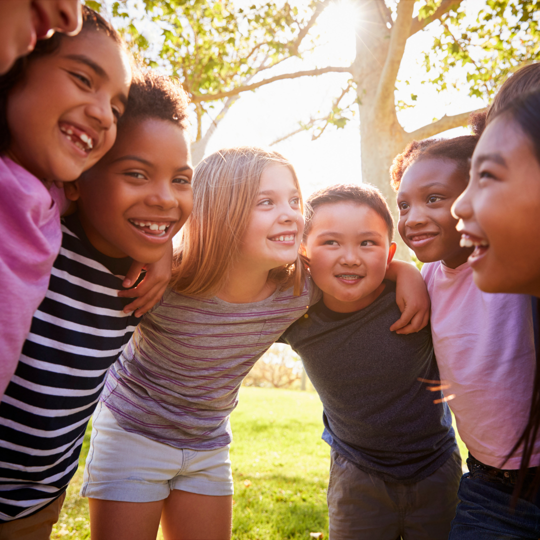 A group of children are hugging each other in a park.
