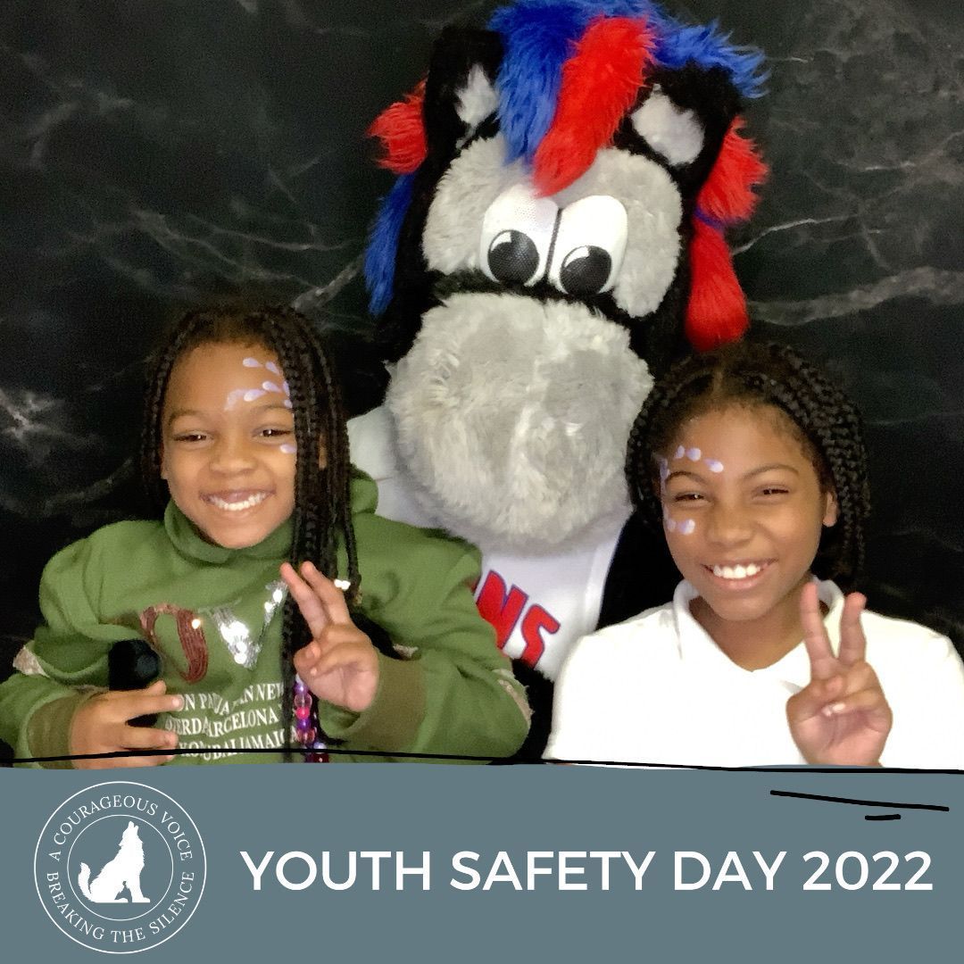 Two smiling children pose with a mascot at Youth Safety Day 2022, making peace signs.
