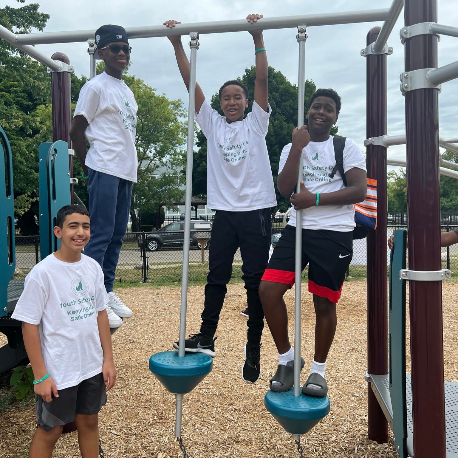 Five people posing on playground equipment, with two hanging from bars and three standing nearby.