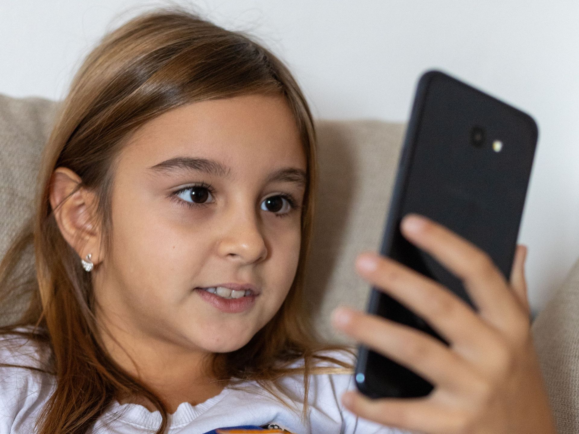 Girl on a couch holding a smartphone and looking at the screen