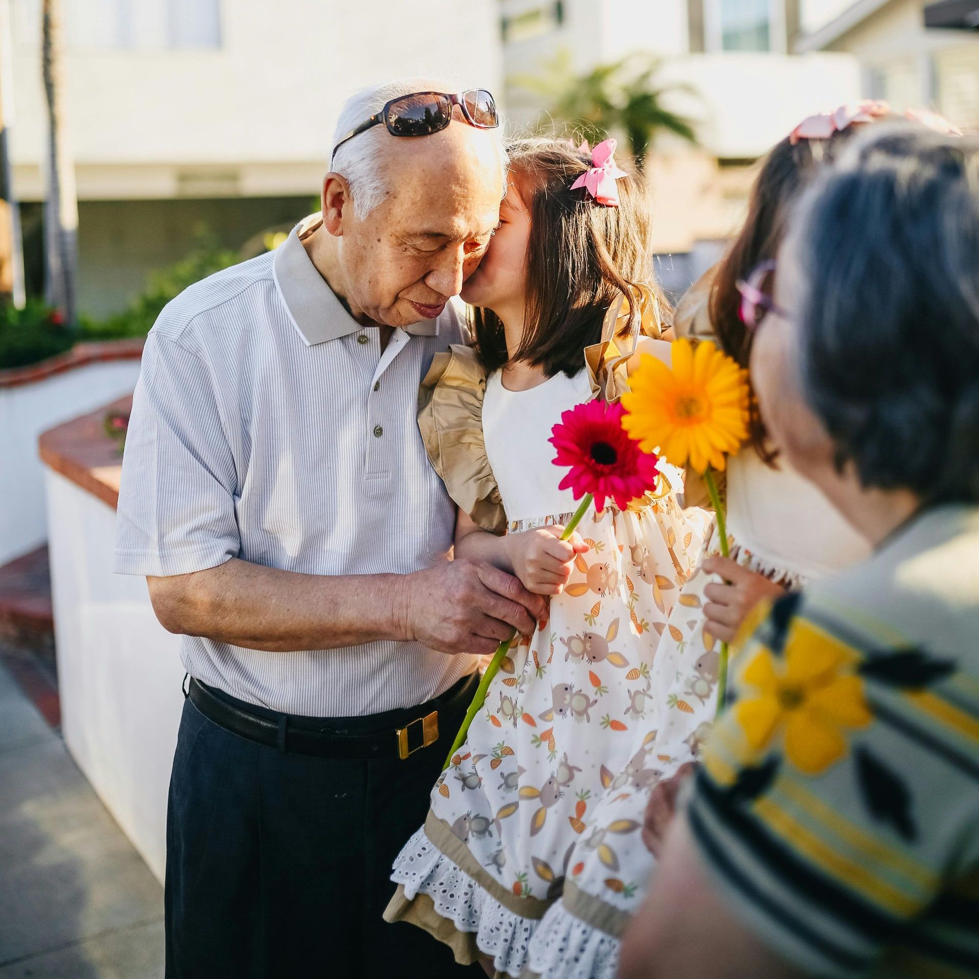 A man kisses a little girl on the cheek while holding flowers
