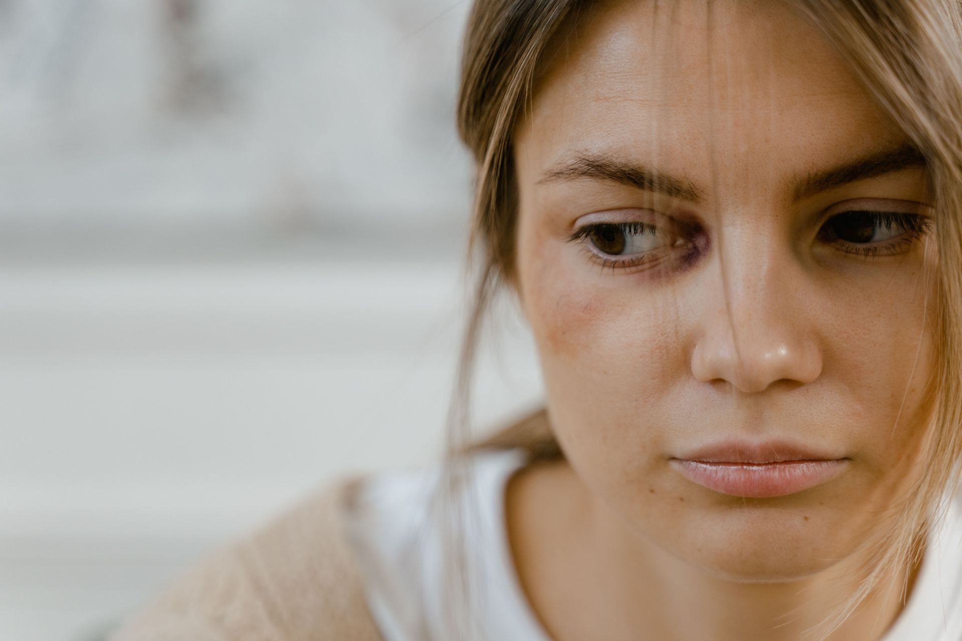 Close-up of a woman looking down pensively against a soft gray background