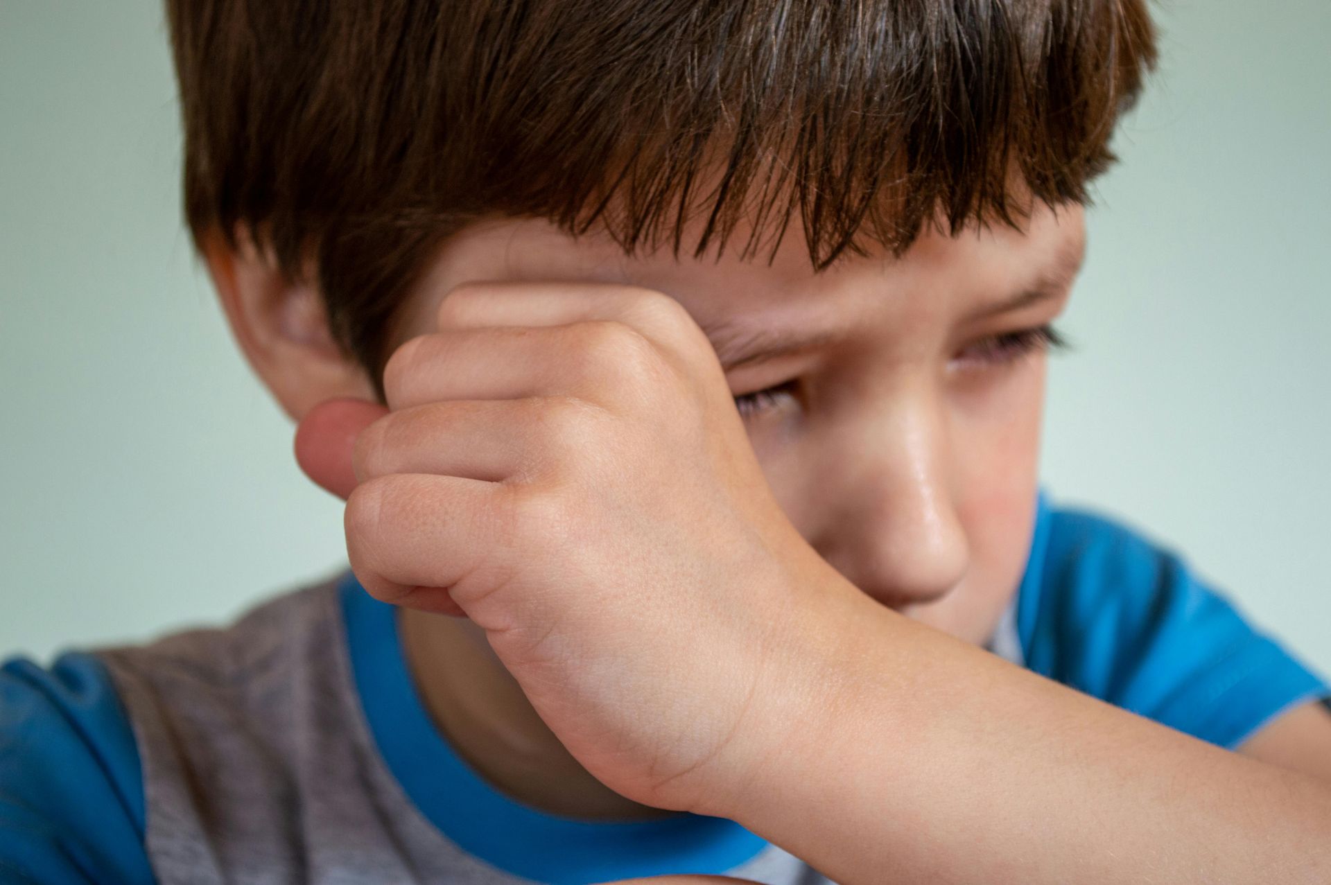 A child wiping away tears with his hand.