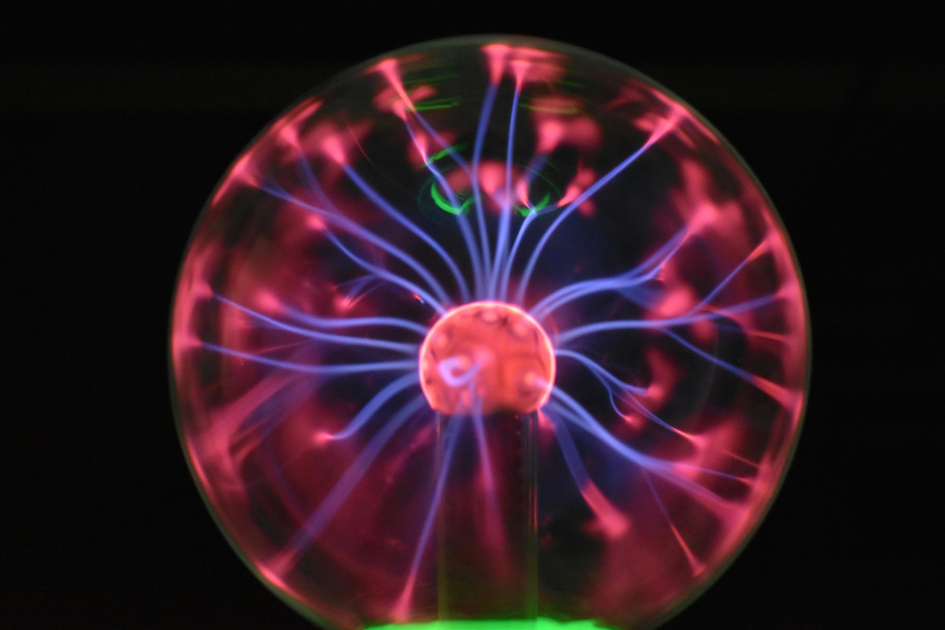 A plasma globe with glowing purple and pink electrical filaments radiating from a central electrode.