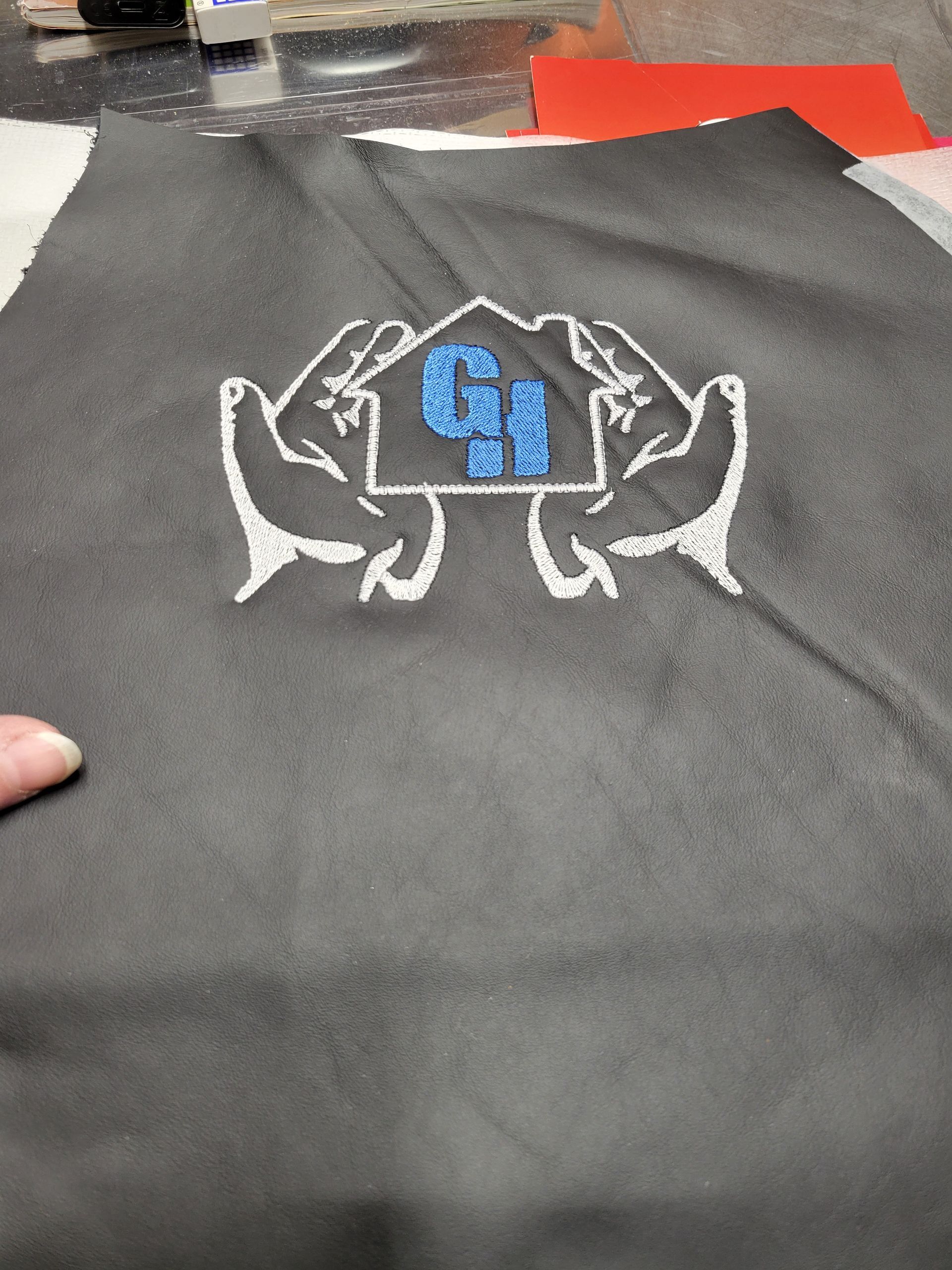 A person is holding a piece of cloth with a drawing of a house on it.
