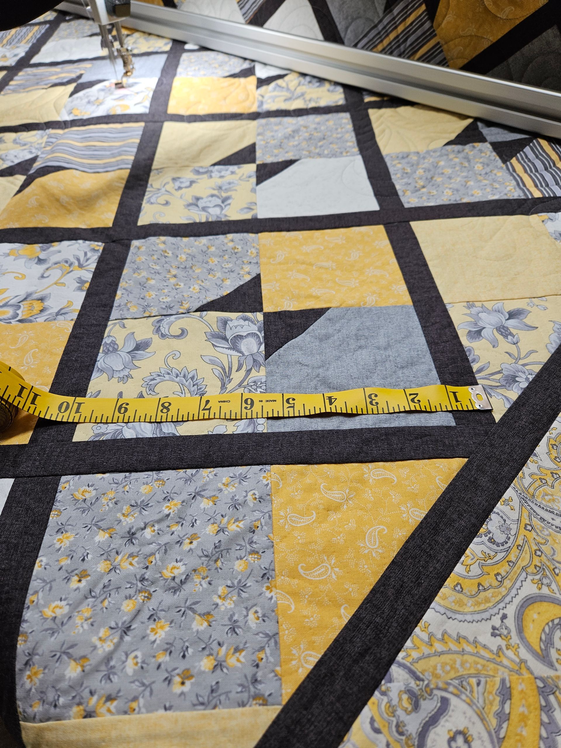 A tape measure is laying on top of a quilt.