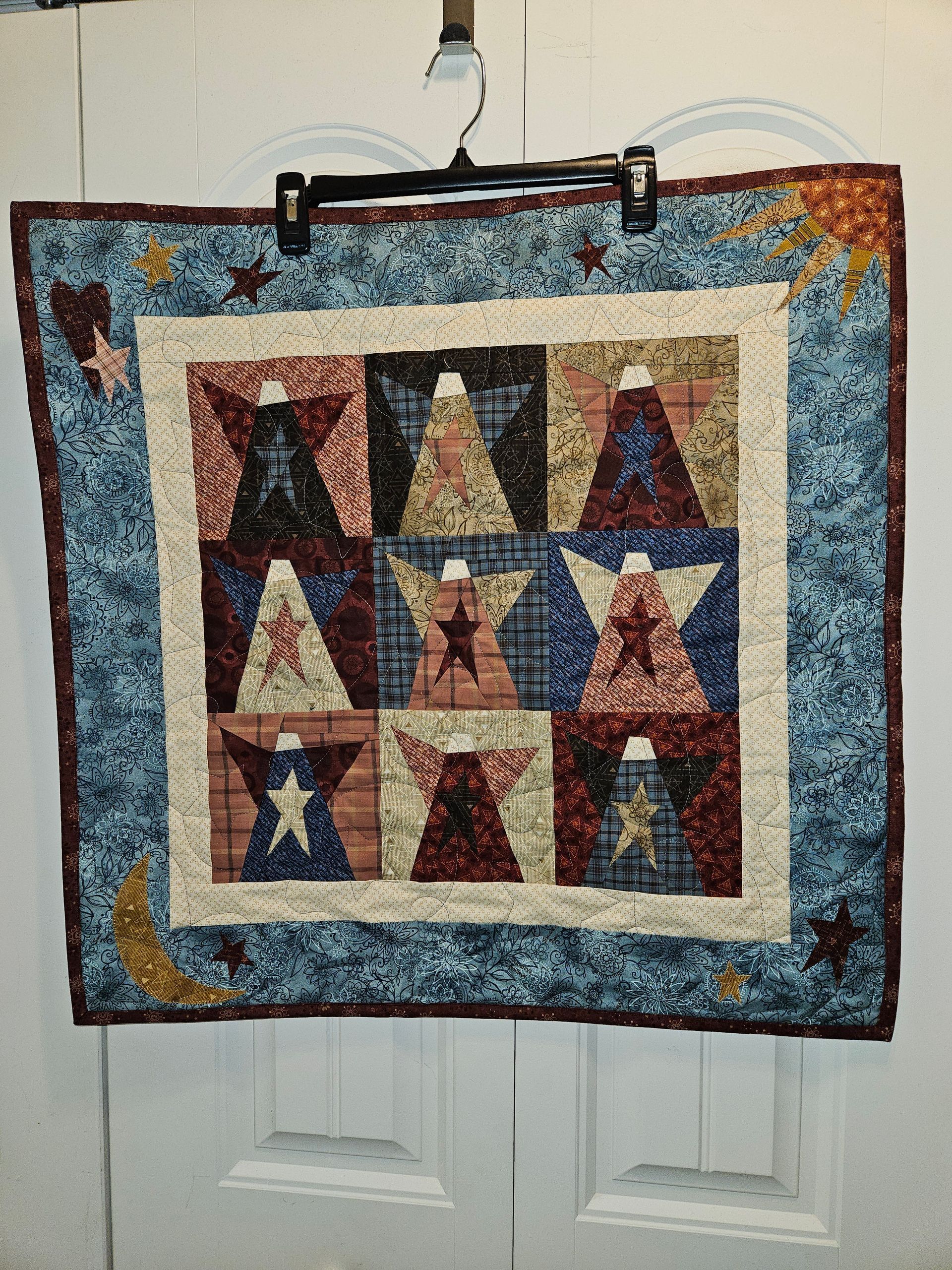A quilt is hanging on a door with a hanger