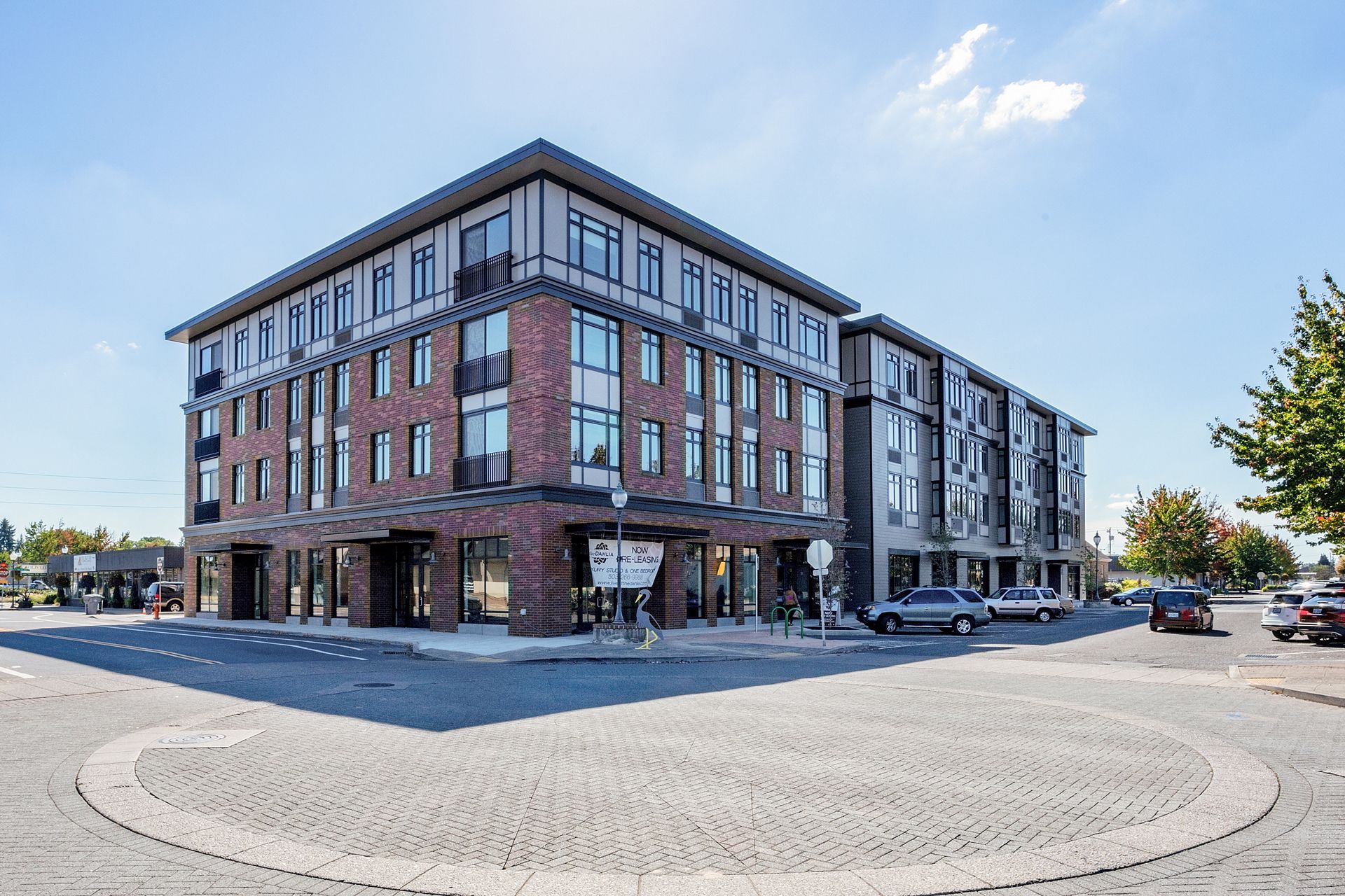 A large brick building with a lot of windows is sitting on the corner of a street.