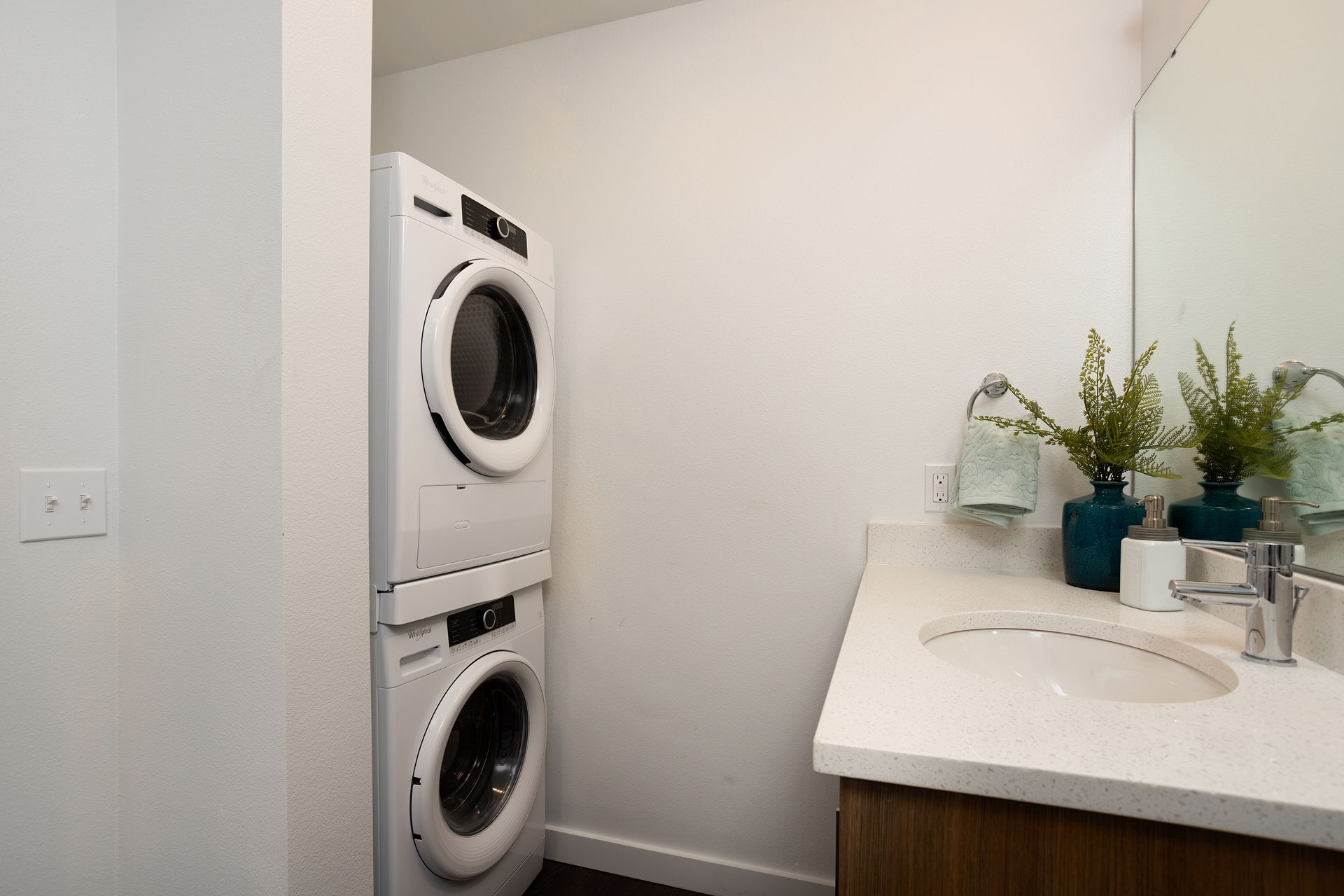 A bathroom with a washer and dryer stacked on top of each other.
