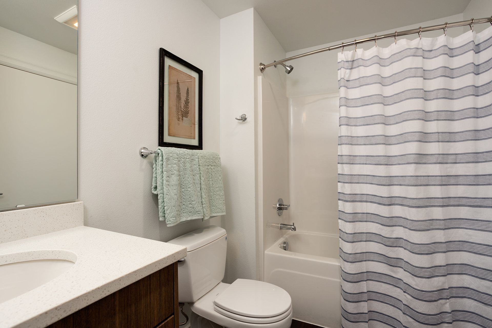 A bathroom with a toilet , sink , bathtub and shower curtain.