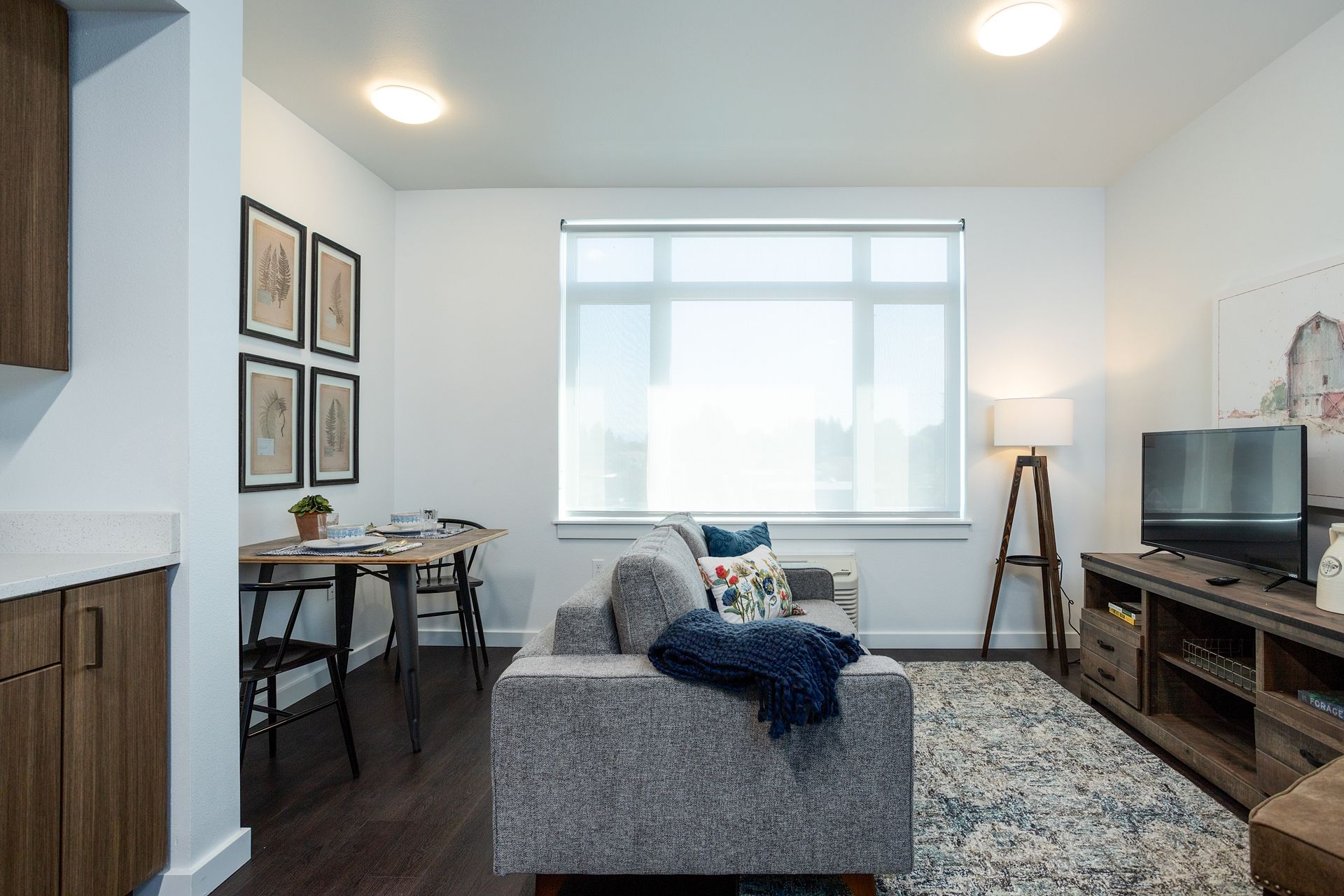A living room with a couch , television , table and chairs.