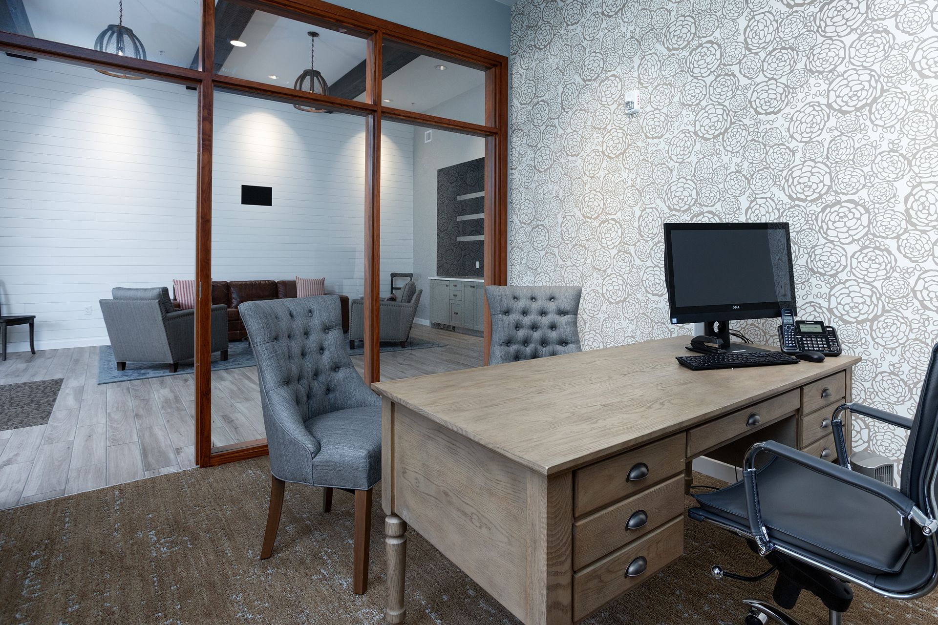 An office with a desk , chairs , and a computer.