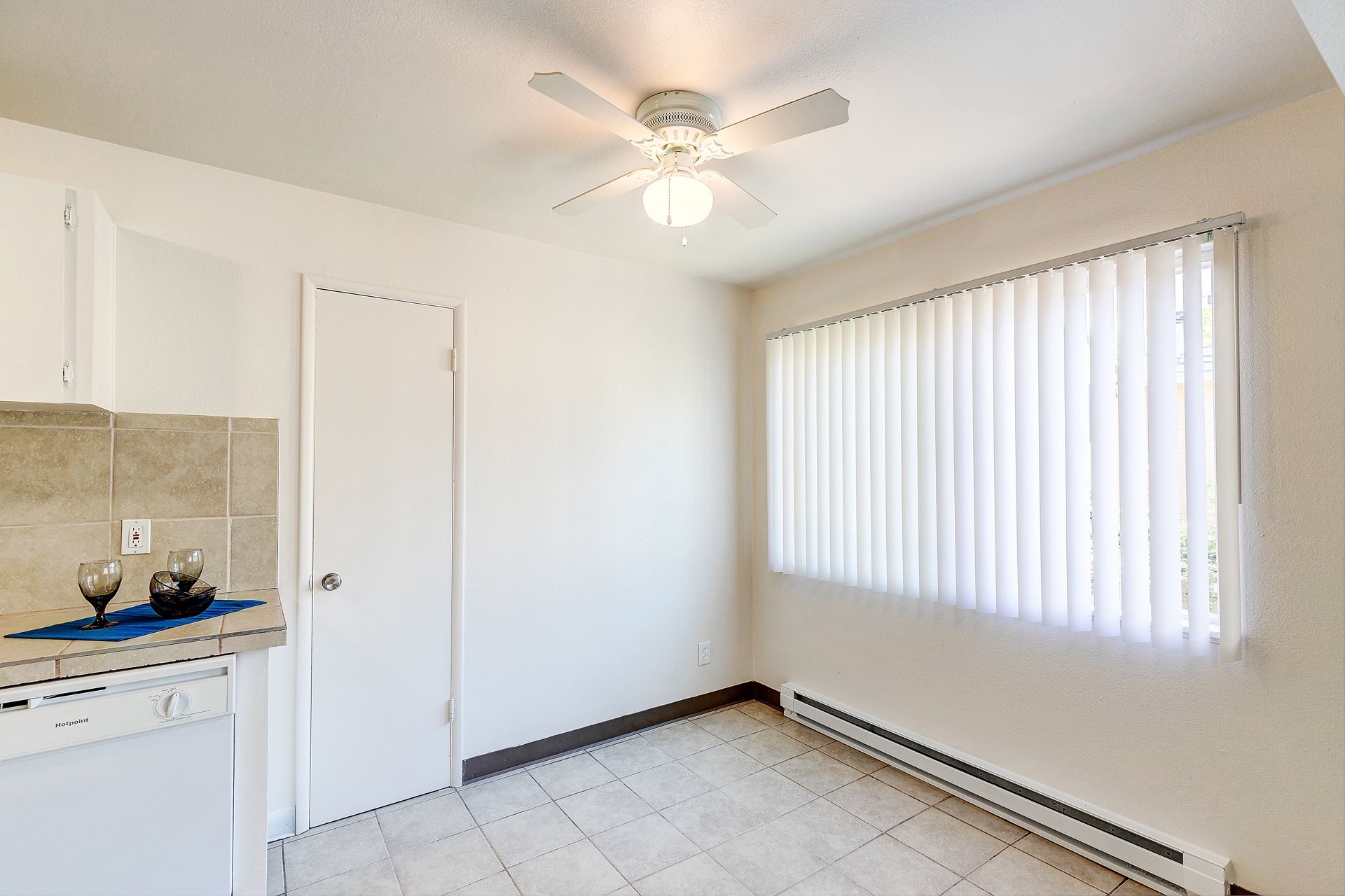 An empty room with a ceiling fan and a window