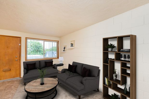 A living room with a table and chairs and a kitchen with a refrigerator and stove