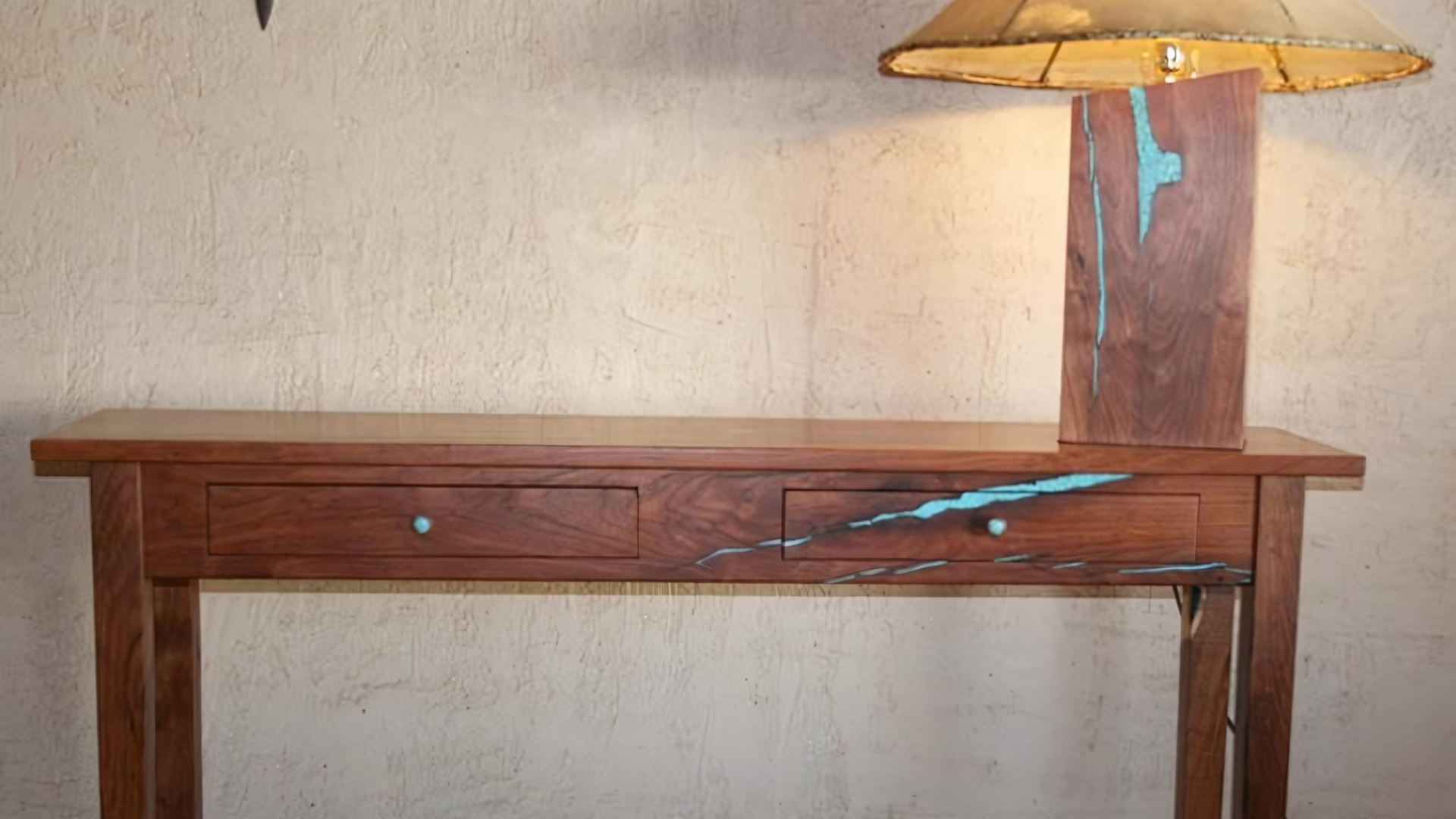 Rustic wooden table with a lamp and blue decorative branch on a plain wall backdrop