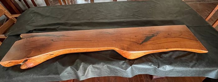 Wooden serving tray with dark bark edges on a black plastic-covered surface