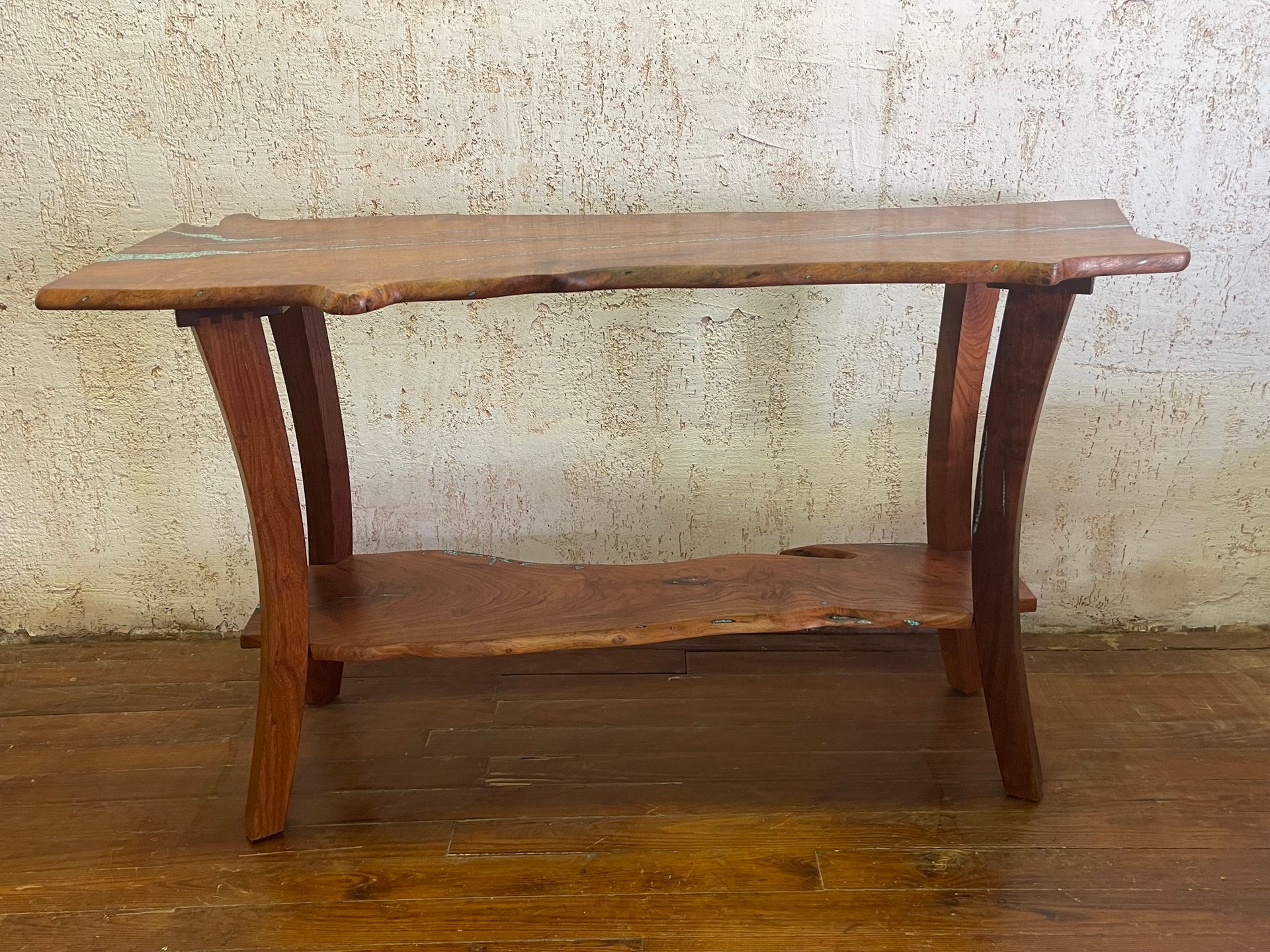 Rustic wooden console table with curved legs against a textured wall