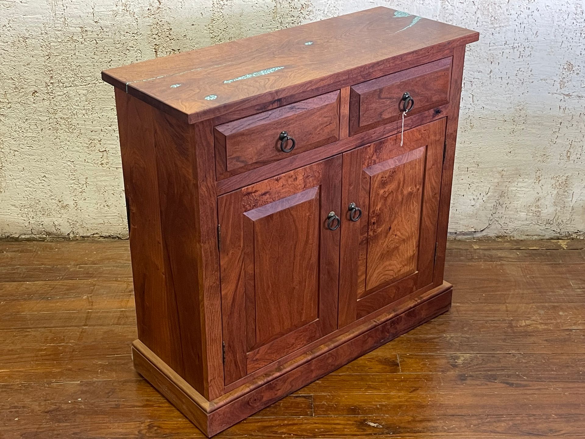 Wooden cabinet with two drawers and double doors on a hardwood floor against a wall