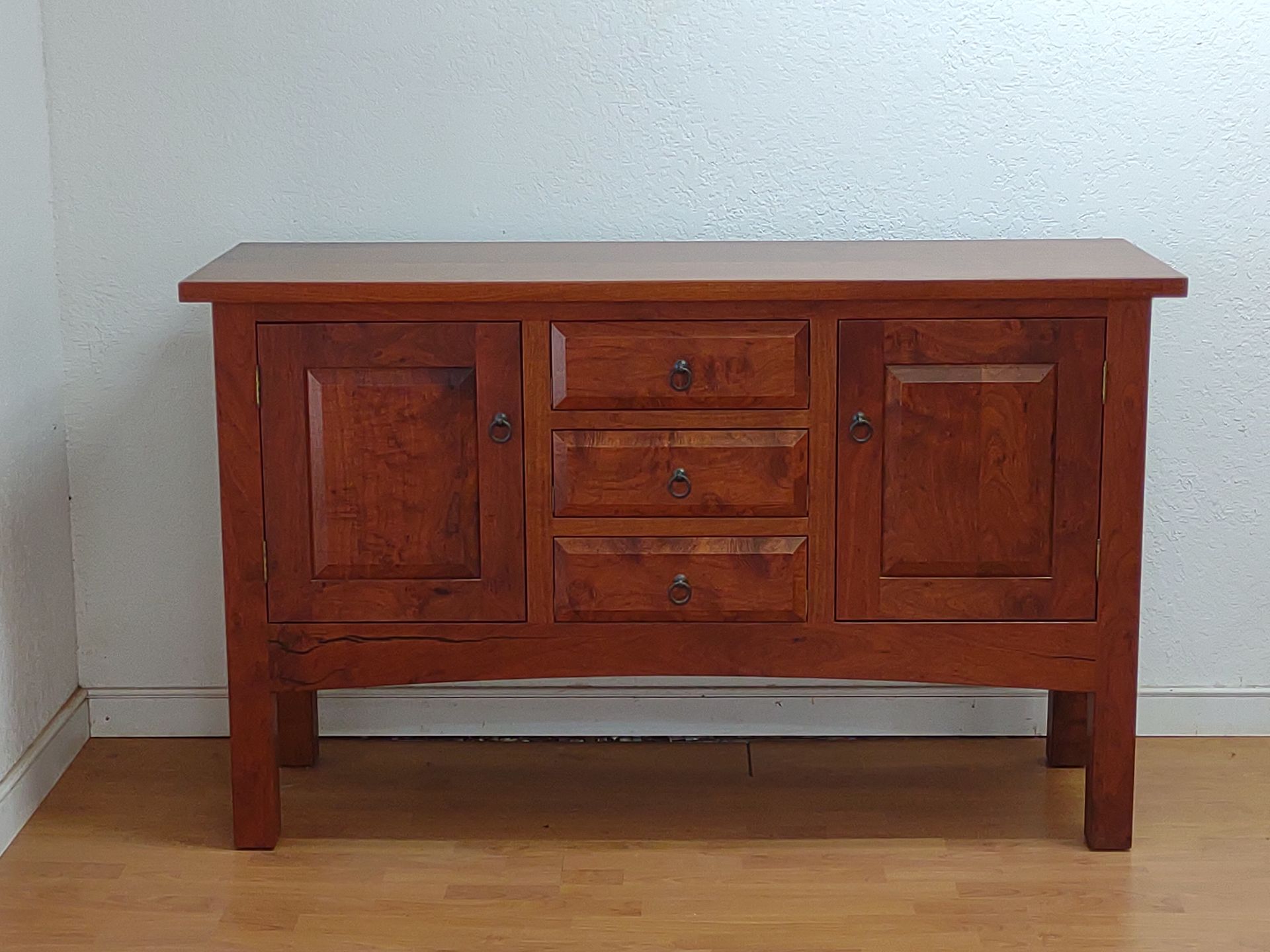 Wooden sideboard cabinet with drawers and cabinet doors against a white wall