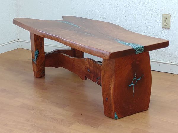 Rustic wooden bench with turquoise metal accents on a light wood floor against a wall