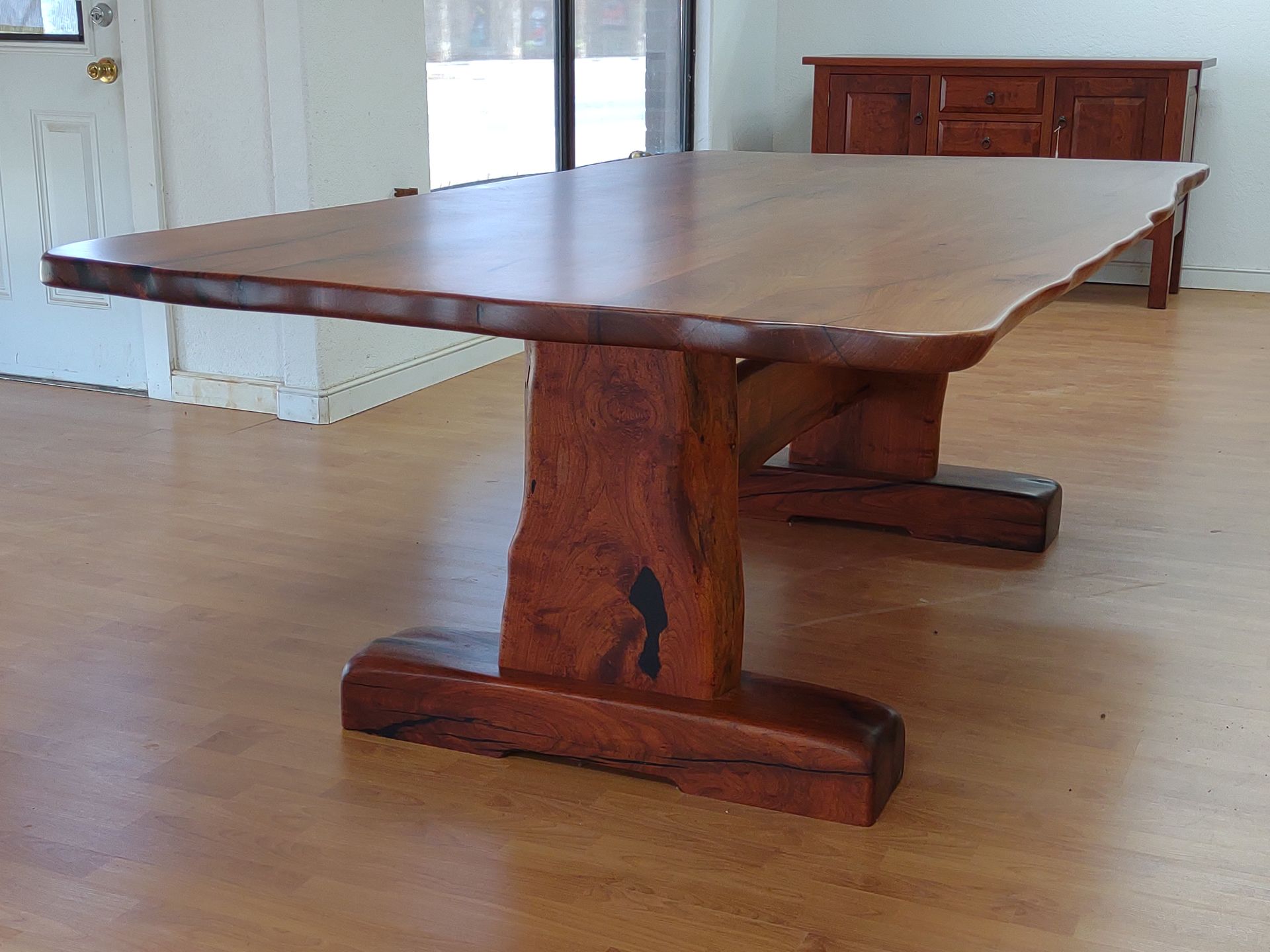 Large wooden conference table in a bright room with wood floors and paneled bench seating