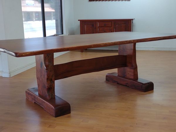 Rustic wooden dining table with thick trestle base in a bright empty room