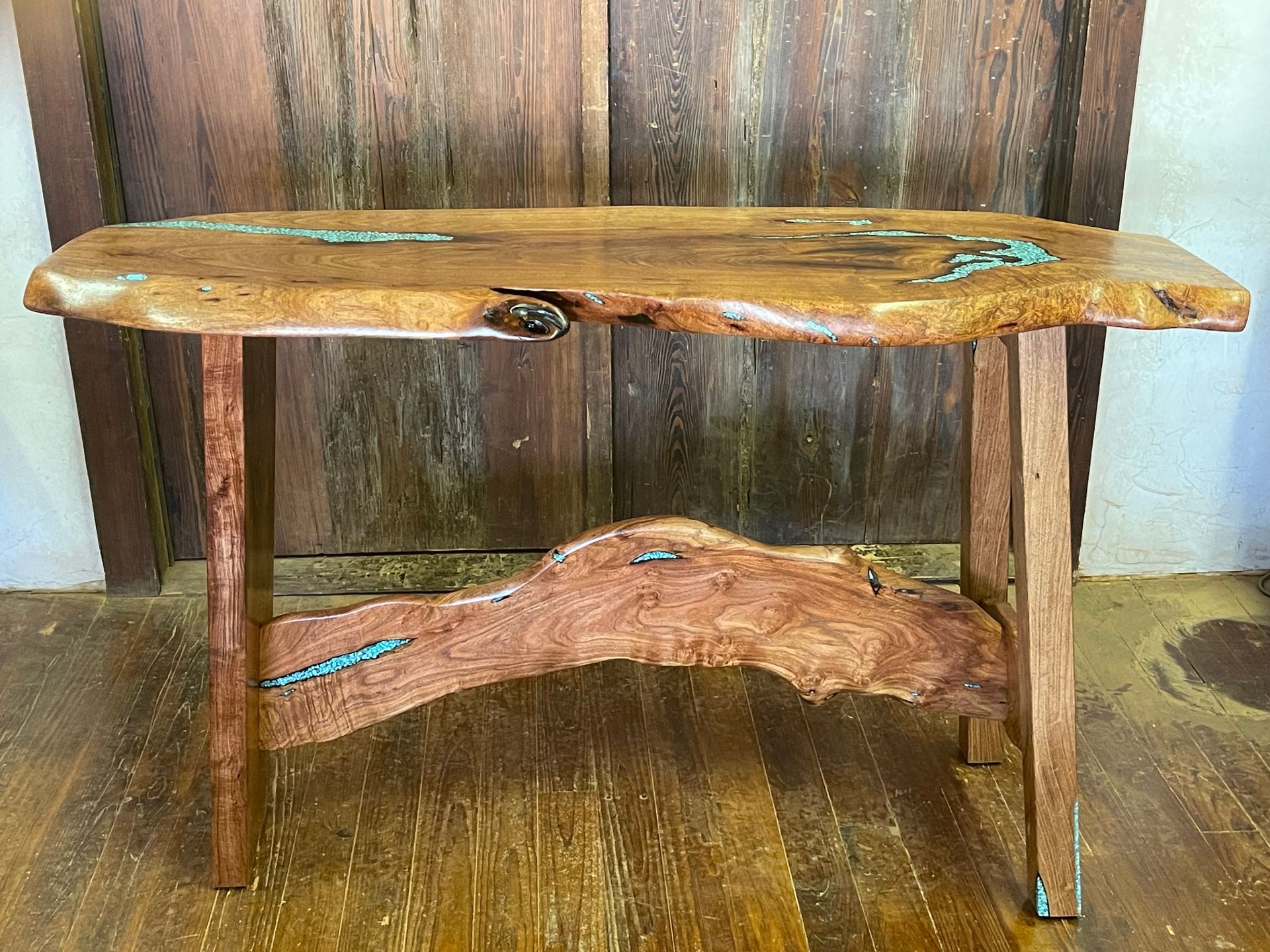 Rustic live-edge wooden bench with turquoise accents against a wood-paneled wall