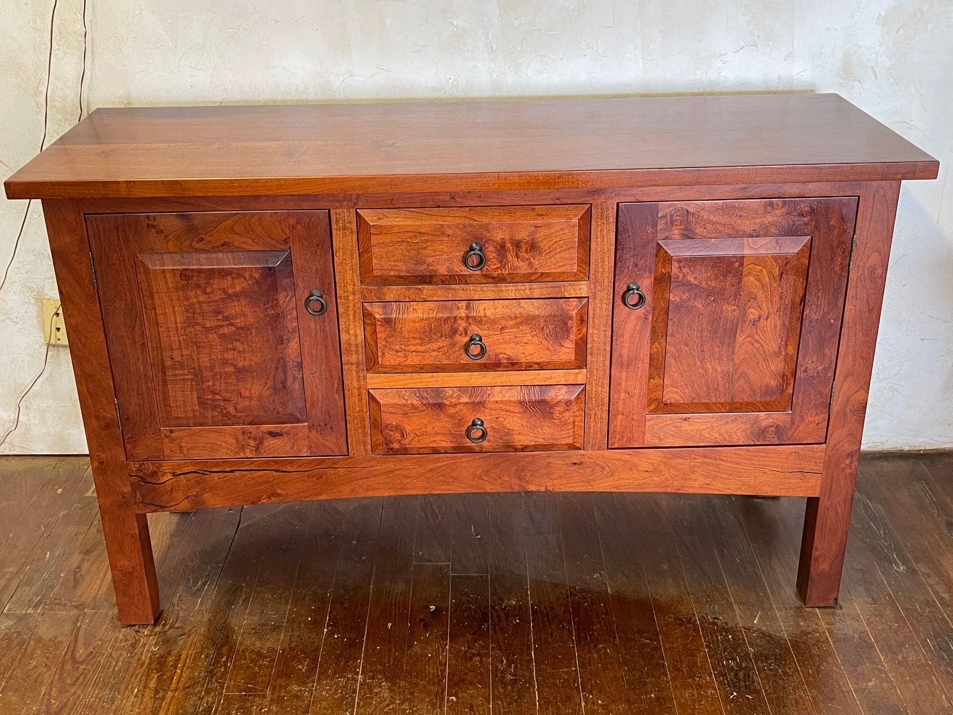Wooden antique sideboard with two cabinet doors and three central drawers on a tiled floor.