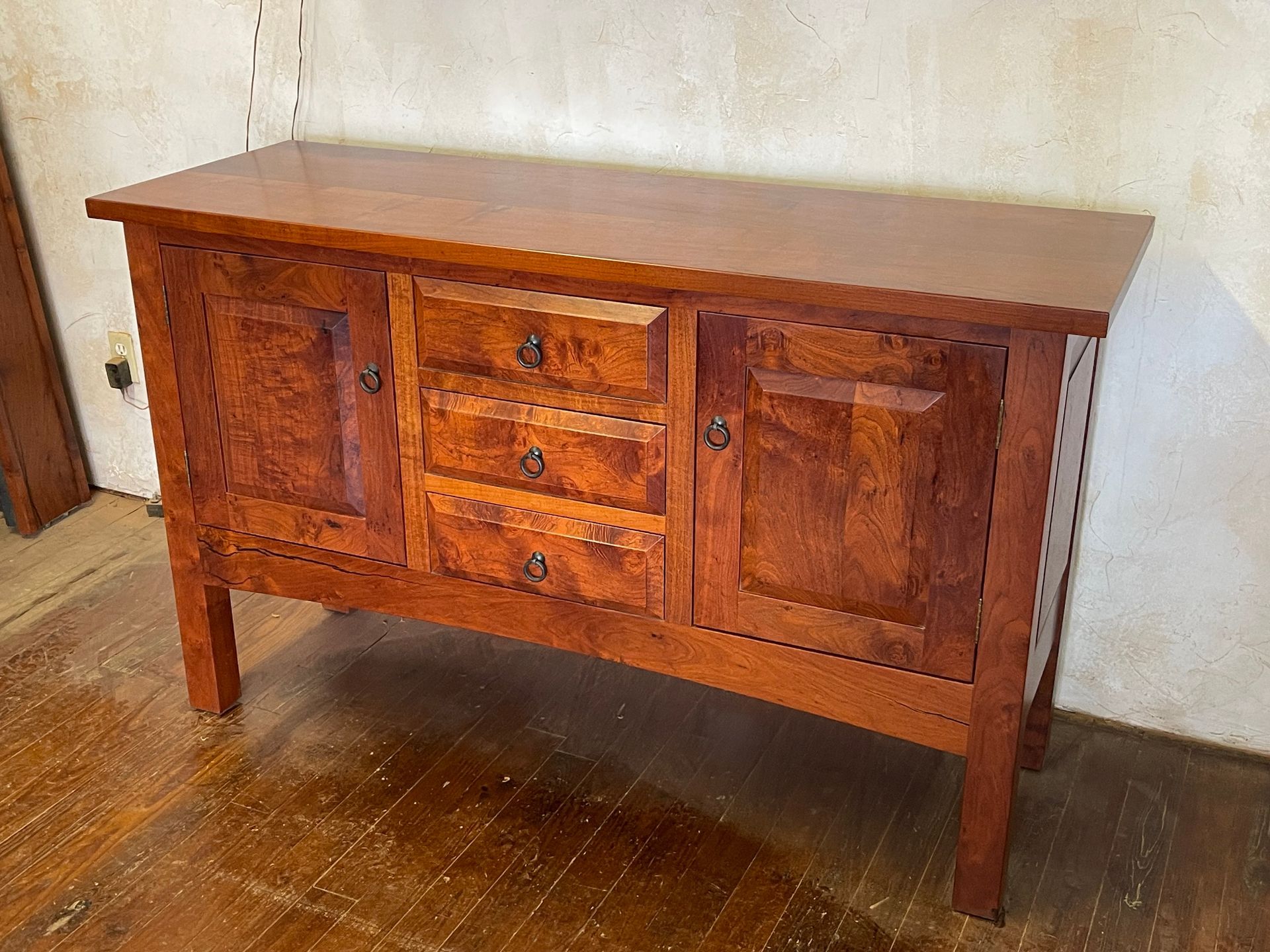 Wooden sideboard cabinet with drawers and cabinets on a hardwood floor against a wall
