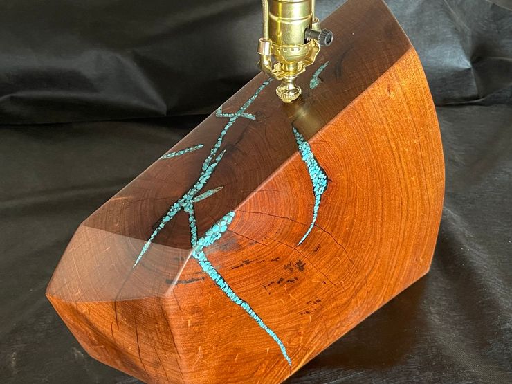 Golden metal nozzle engraving blue lines on a polished wooden block